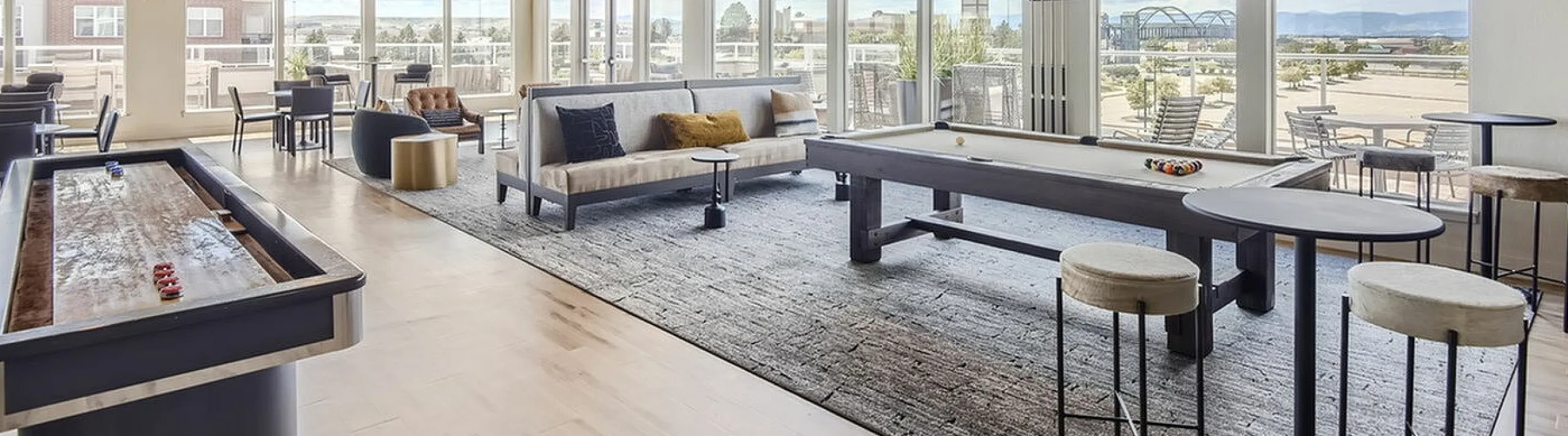 Elegant recreational room with billiards and shuffleboard, featuring modern furnishings and panoramic windows, perfect for entertainment and relaxation.