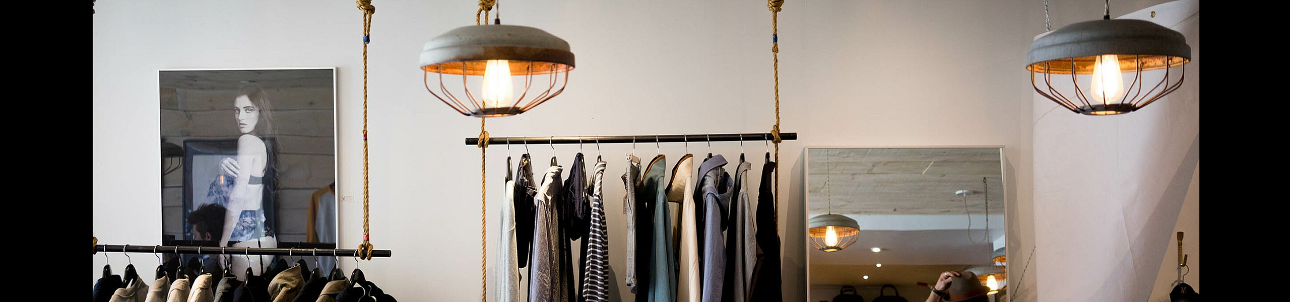 Chic boutique interior showcasing stylish clothing selection on industrial racks under warm pendant lighting.