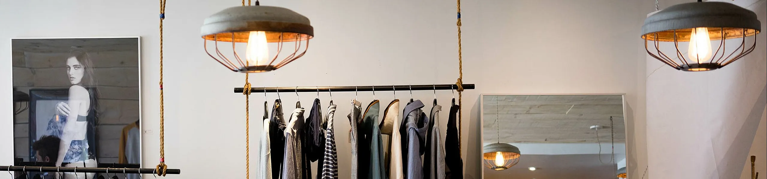 Chic modern boutique interior featuring stylish hanging light fixtures and a curated selection of trendy clothing on display.