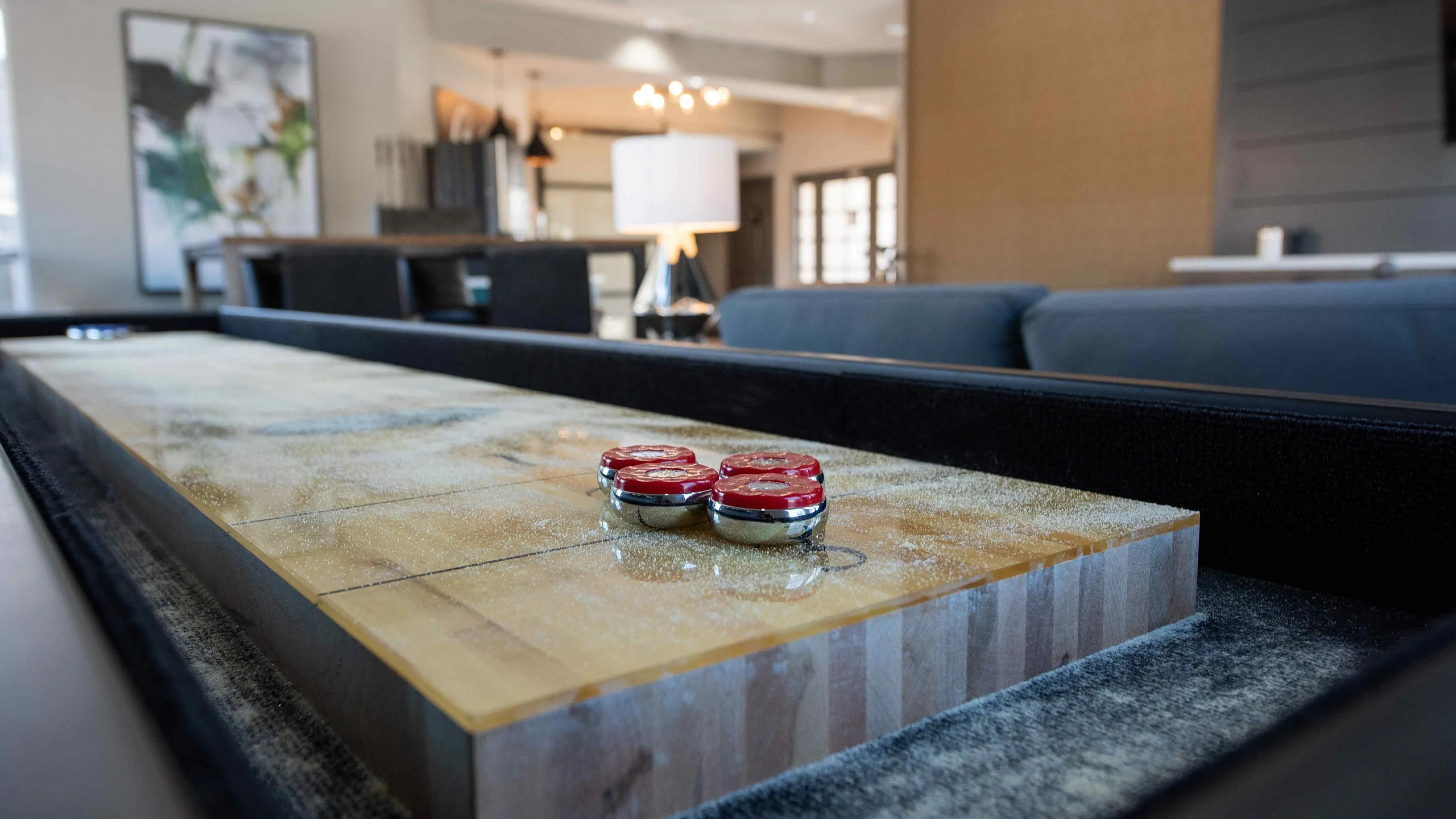 Modern living area with a stylish shuffleboard table, chic decor, and ambient lighting.