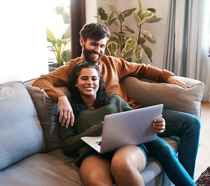 Cozy living room with a couple relaxing on a comfortable couch, surrounded by lush indoor plants, enjoying a serene and inviting atmosphere.