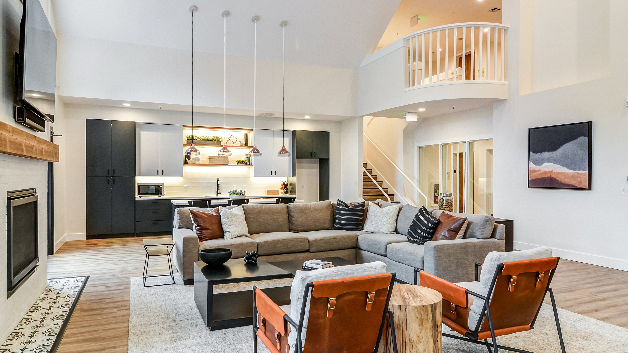 Elegant open-concept living room with contemporary furnishings, featuring a cozy sectional, modern kitchen, and stylish pendant lighting.