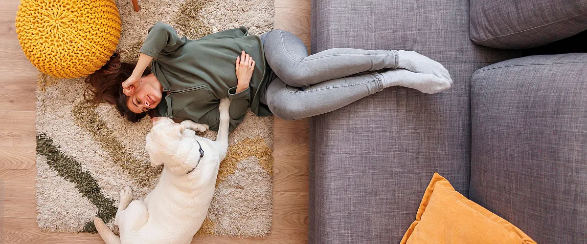 Cozy living space with modern decor, featuring a woman relaxing on a plush rug with her adorable dog beside a stylish sofa and vibrant accents.
