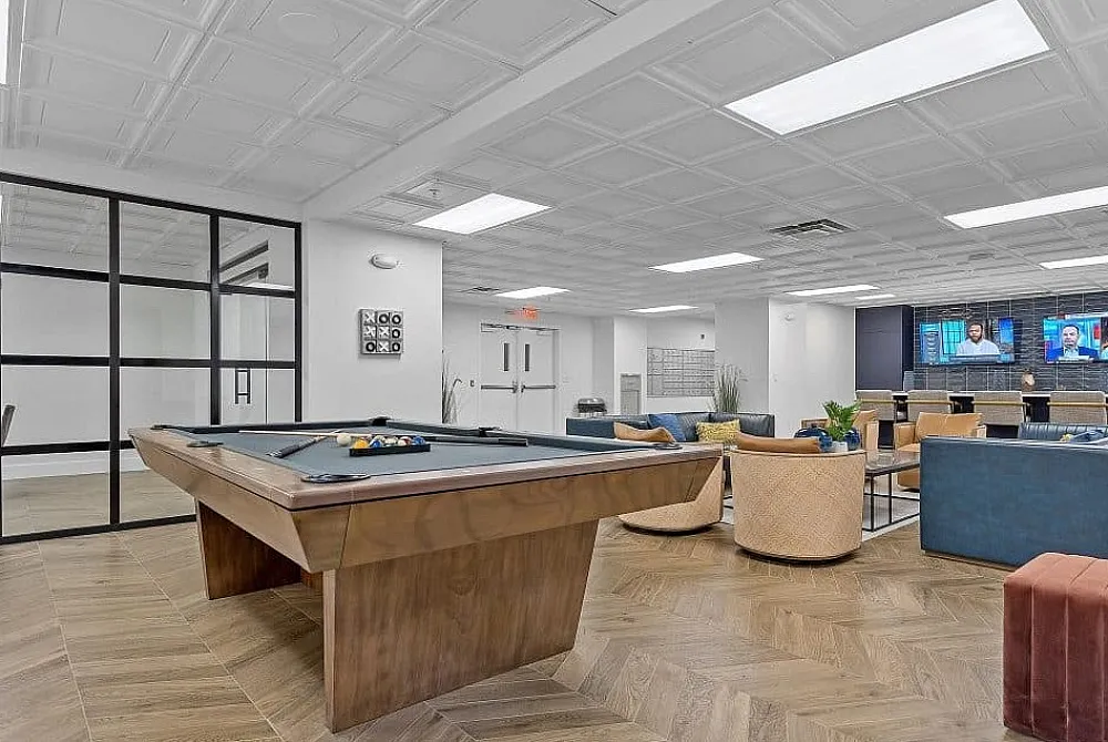 Modern recreation room with a stylish pool table, cozy seating area, and large screen TVs, perfect for relaxation and socializing.
