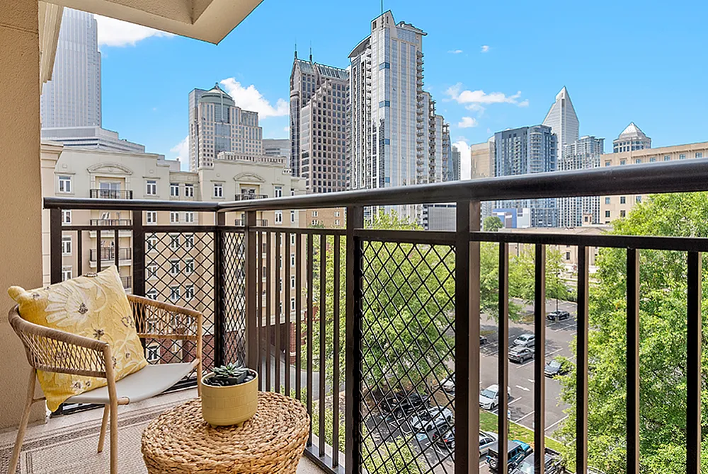 Charming balcony with cozy seating, offering stunning city skyline views and lush greenery.