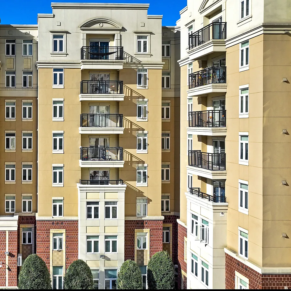 Elegant urban apartment building with stylish balconies and modern architecture, bathed in sunshine.