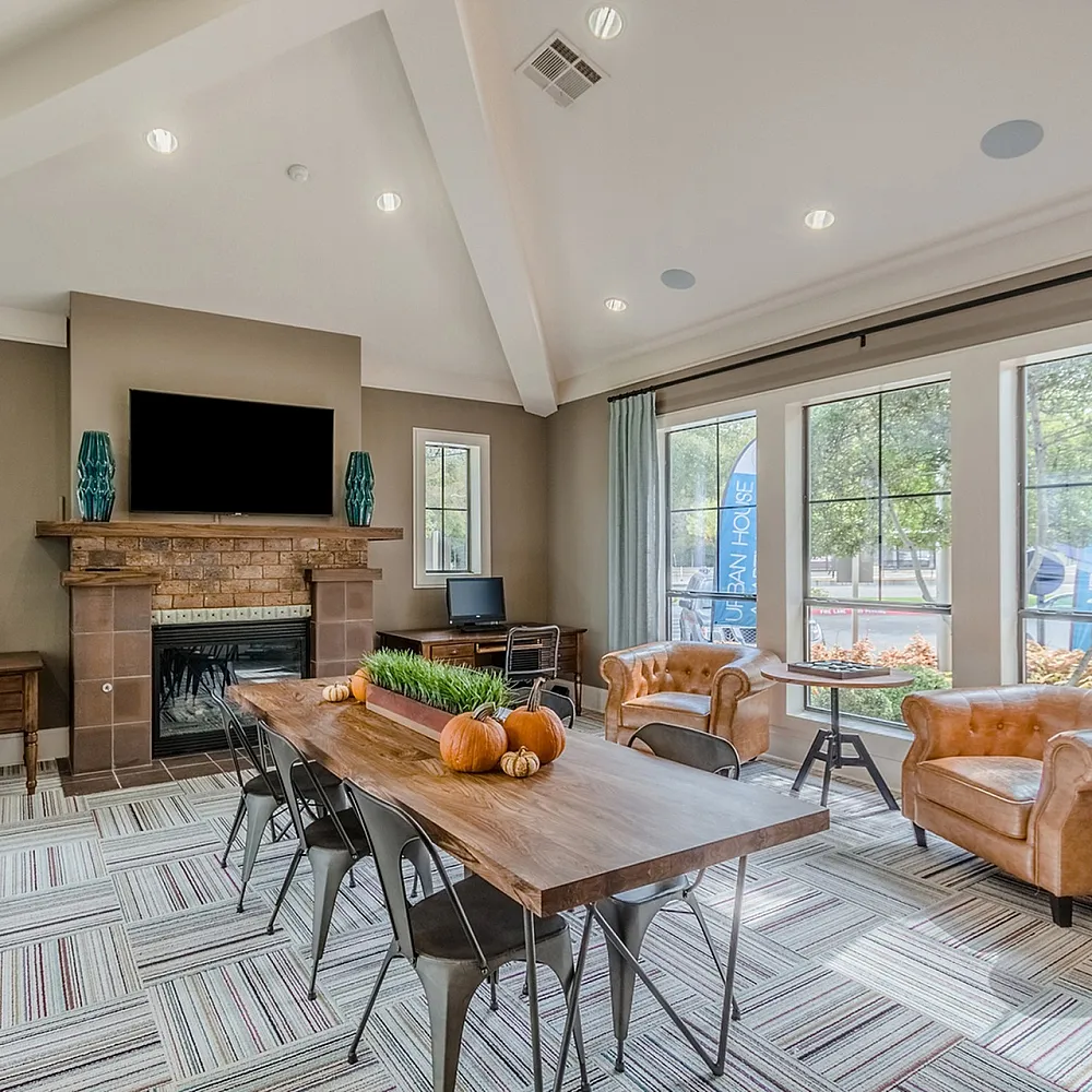 Bright and inviting living area with stylish decor, featuring a cozy fireplace, elegant leather chairs, and a large wooden table perfect for gatherings.