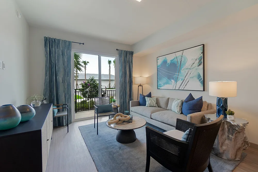 Elegant living room with modern decor, featuring a cozy sofa, abstract artwork, and large window overlooking a lush garden.