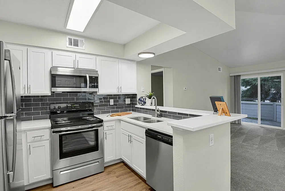 Modern kitchen with sleek stainless steel appliances, elegant cabinetry, and a cozy adjoining living space with natural light.