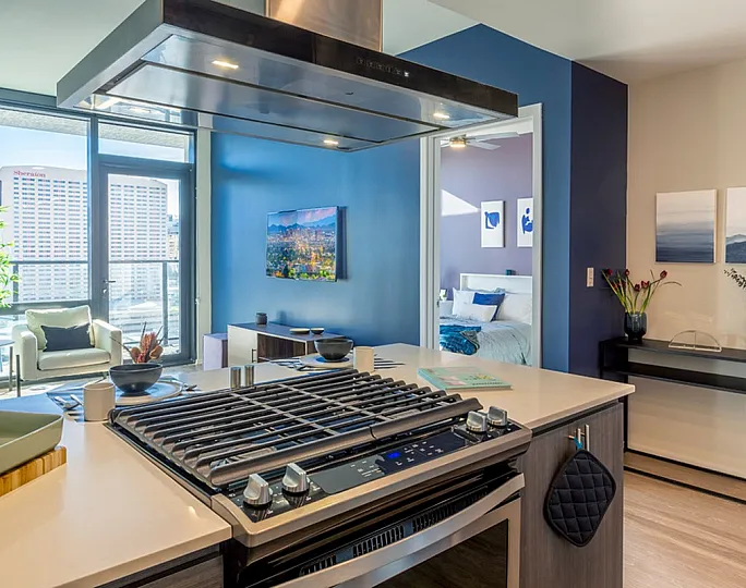 Modern apartment with open kitchen, cozy living area, and chic bedroom view, featuring stylish decor and large windows.
