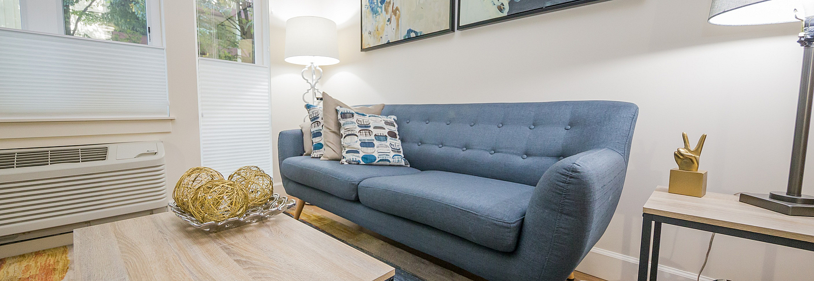 Chic living room with a modern blue sofa, abstract art, and stylish decor, perfect for relaxing in a serene environment.