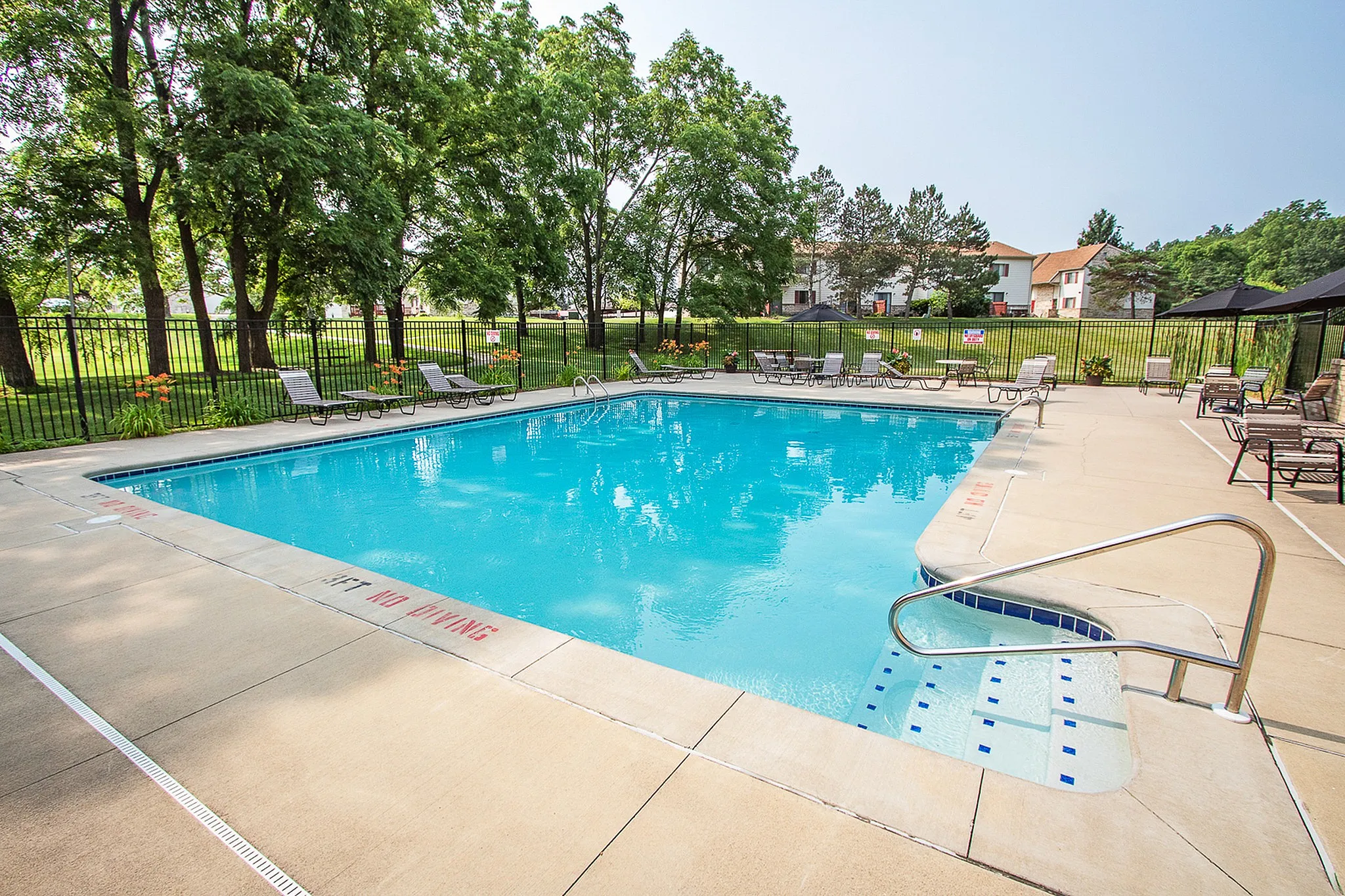 Inviting outdoor pool area surrounded by lush greenery, perfect for relaxation and leisure.