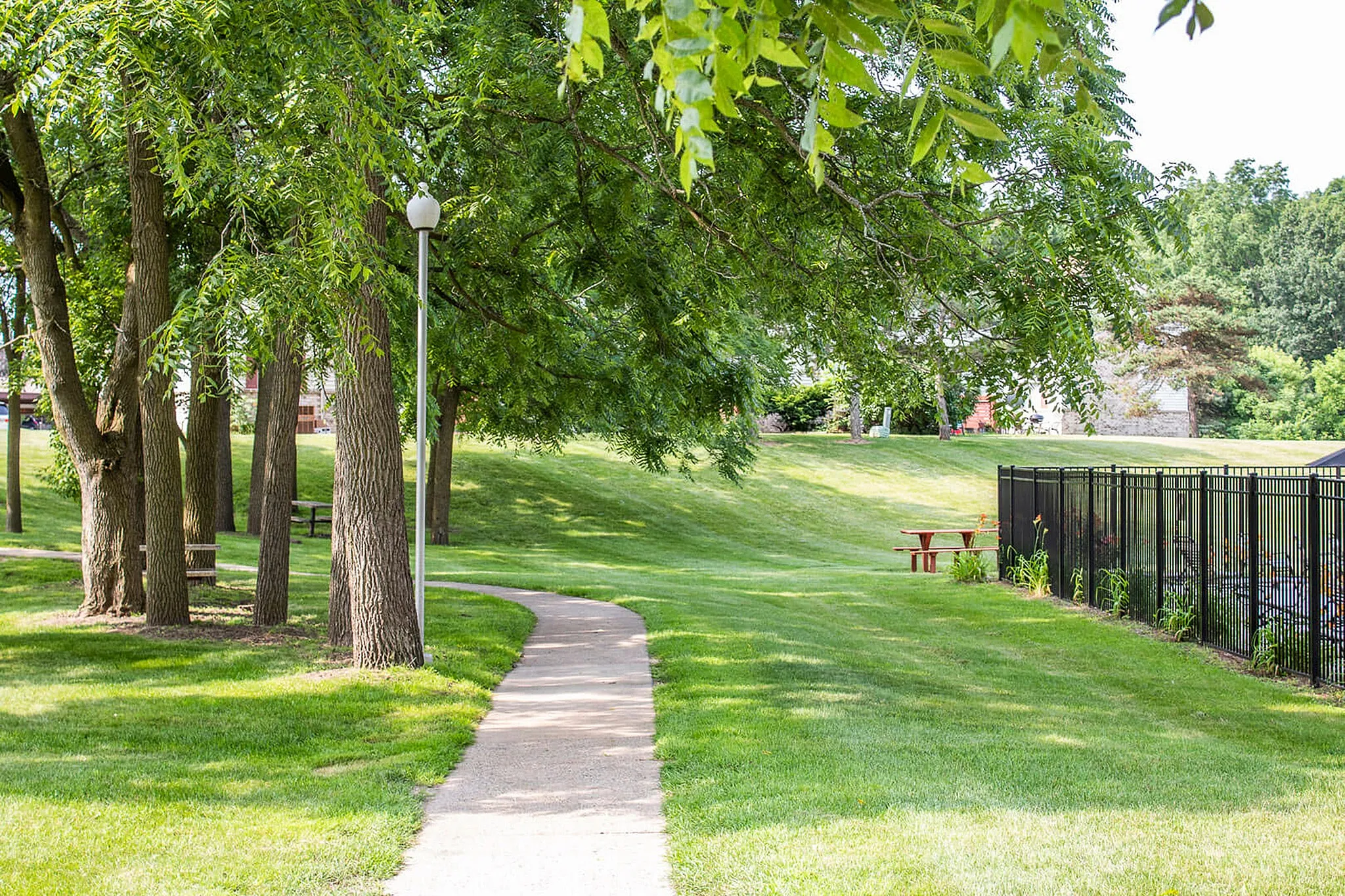 Serene park setting with lush greenery, winding path, and inviting picnic areas, ideal for relaxation and leisure.