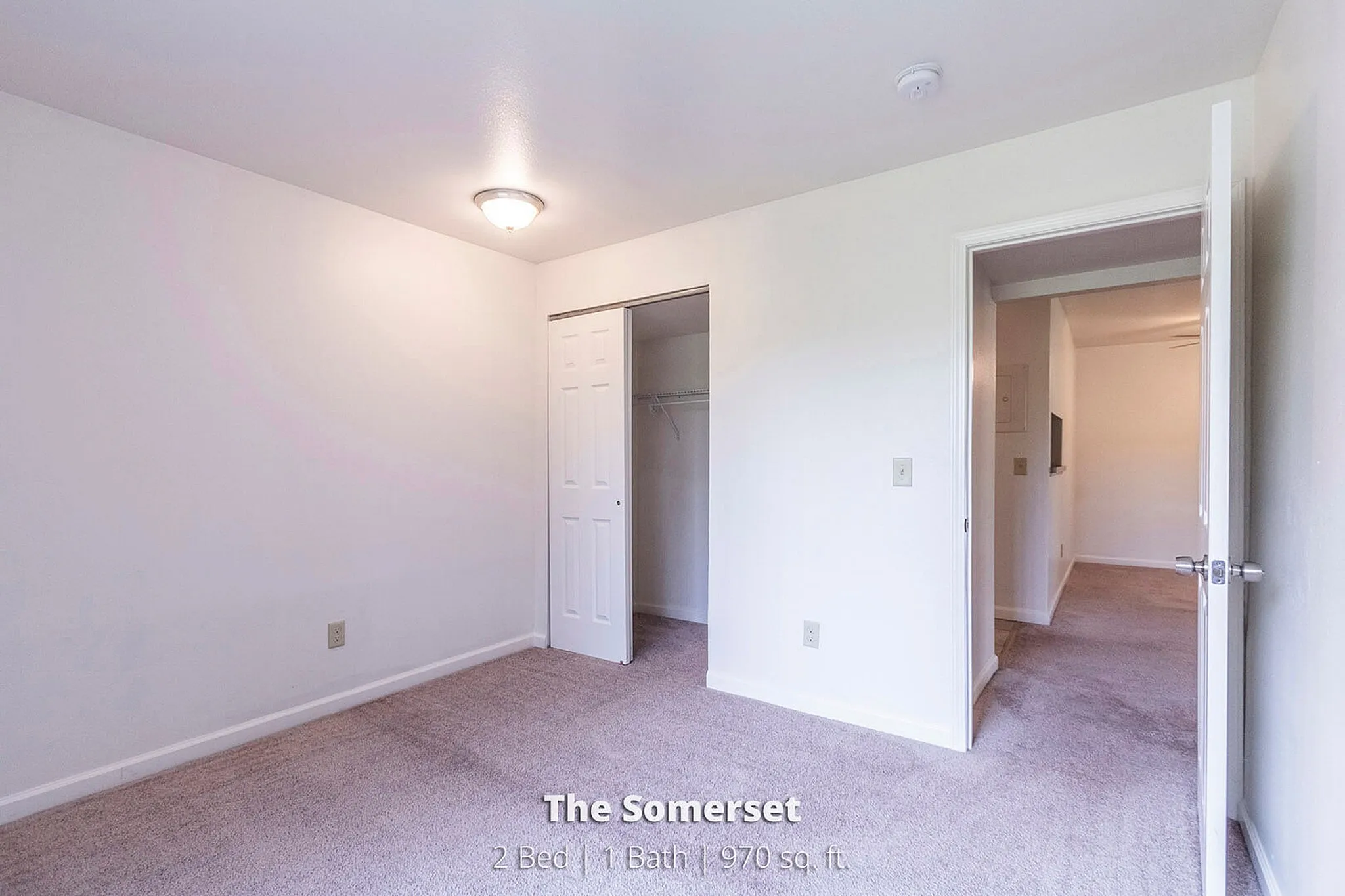 Bright bedroom space in The Somerset apartment featuring soft carpet flooring and ample closet storage, perfect for a cozy living experience in a 2 bed, 1 bath layout spanning 970 sq. ft.