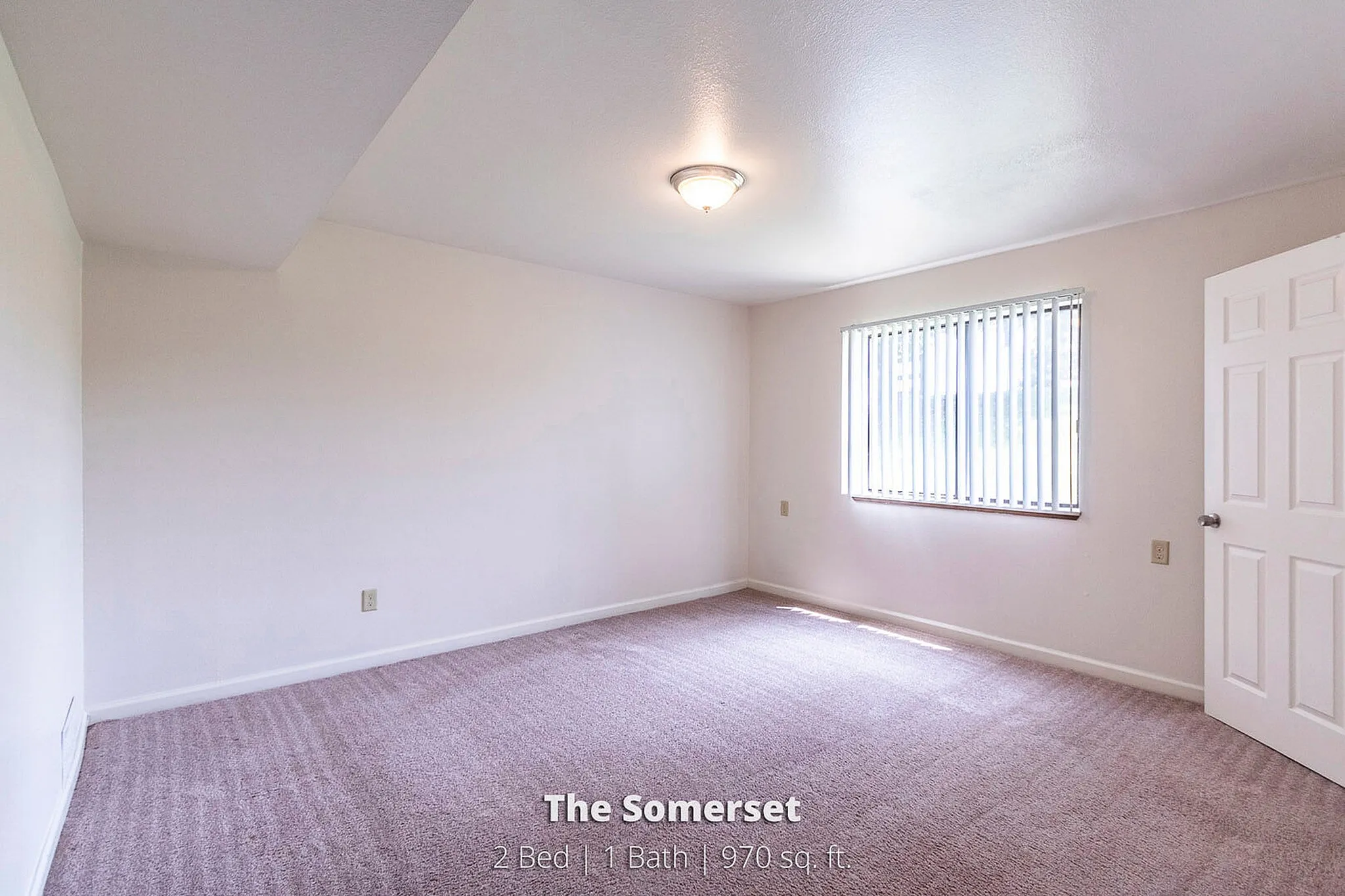 Spacious bedroom in The Somerset apartment, showcasing ample natural light, cozy carpeting, and modern design in a 2 bed, 1 bath layout of 970 sq. ft.