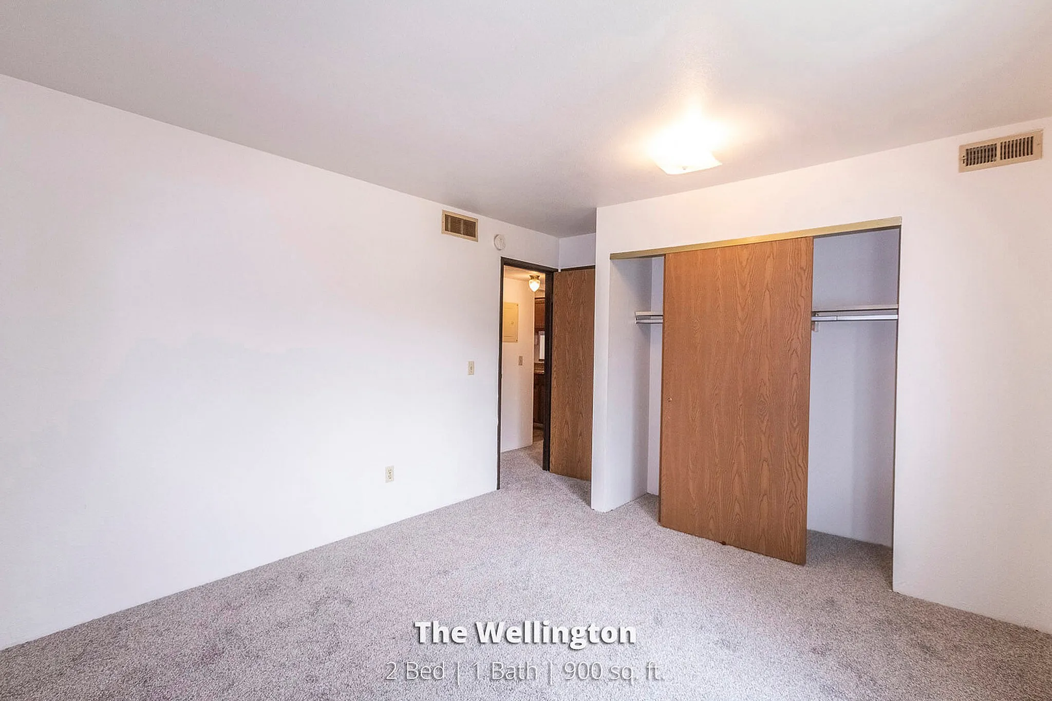 Bright and inviting bedroom at The Wellington with ample closet space, showcasing a modern design in a 2 bed, 1 bath layout, 900 sq. ft.