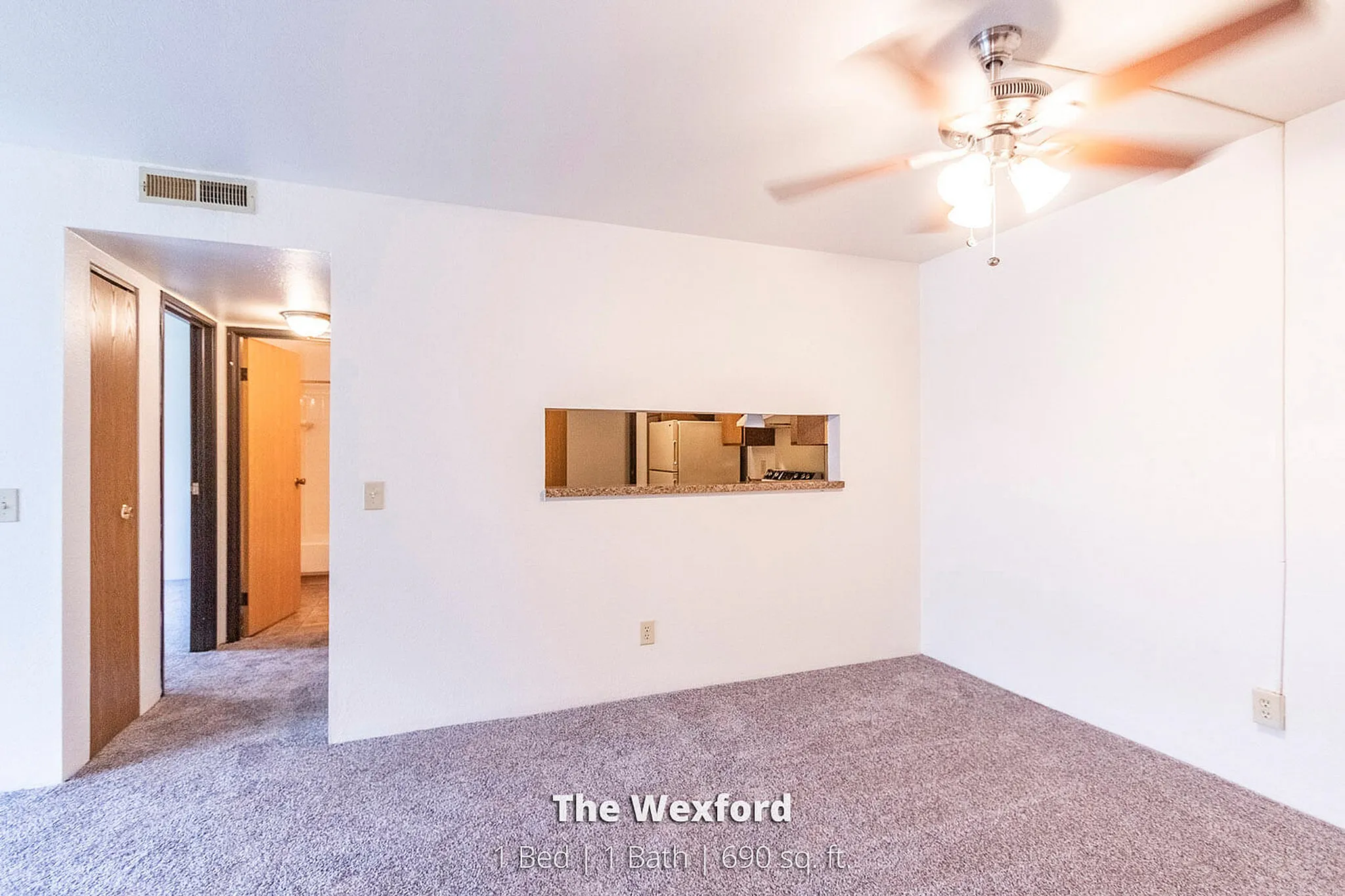 Bright and cozy living space at The Wexford, showcasing a 1-bedroom layout with modern lighting and a peek into the stylish kitchen area.
