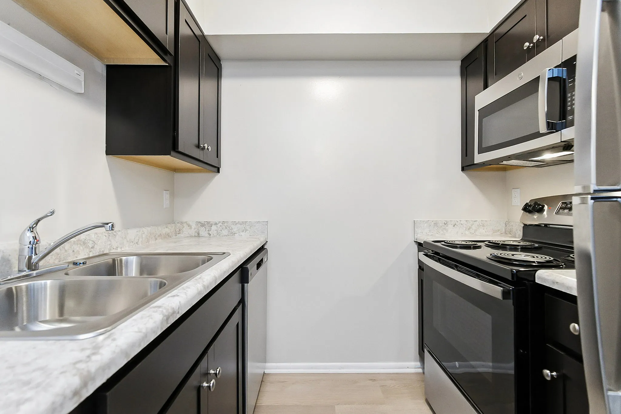 Modern kitchen with sleek black cabinetry, stainless steel appliances, and elegant marble countertops.