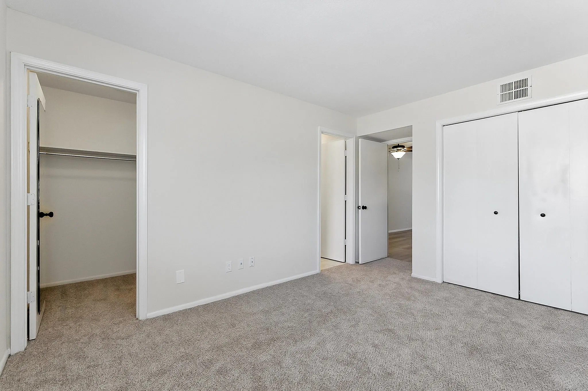 Bright and spacious bedroom featuring soft carpeted flooring, ample closet space, and a fresh modern look, perfect for a cozy retreat.
