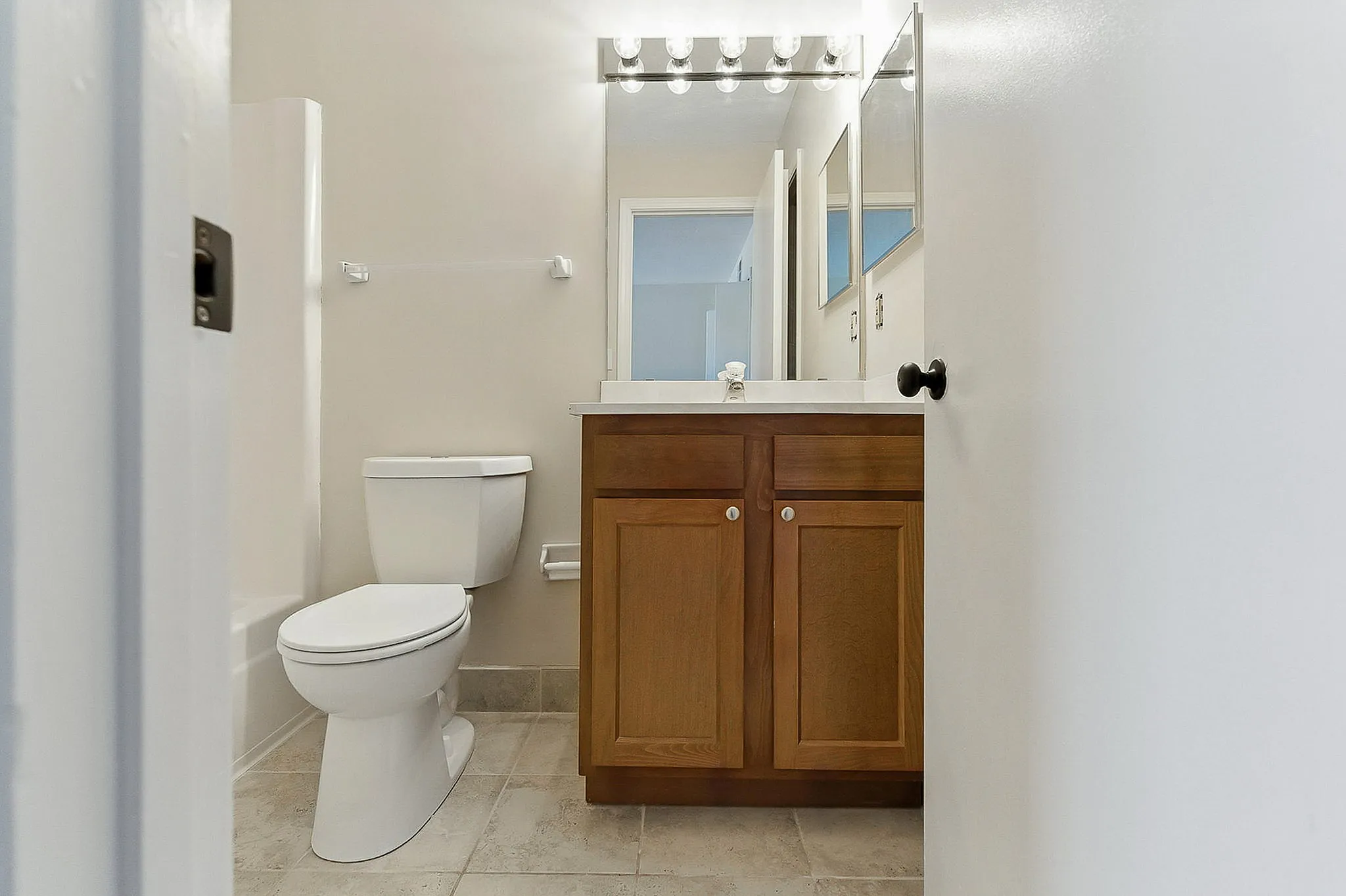 Elegant bathroom with modern fixtures, featuring a chic vanity, large mirror, and pristine tile floor.