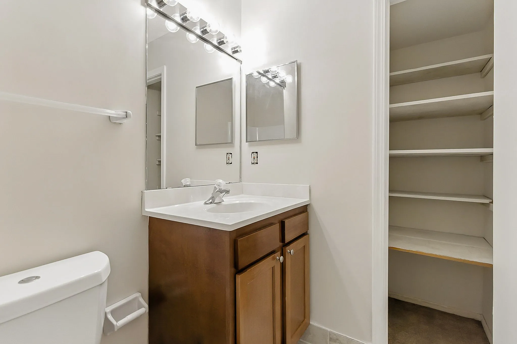 Contemporary bathroom with elegant vanity, large mirror, and ample shelving space.