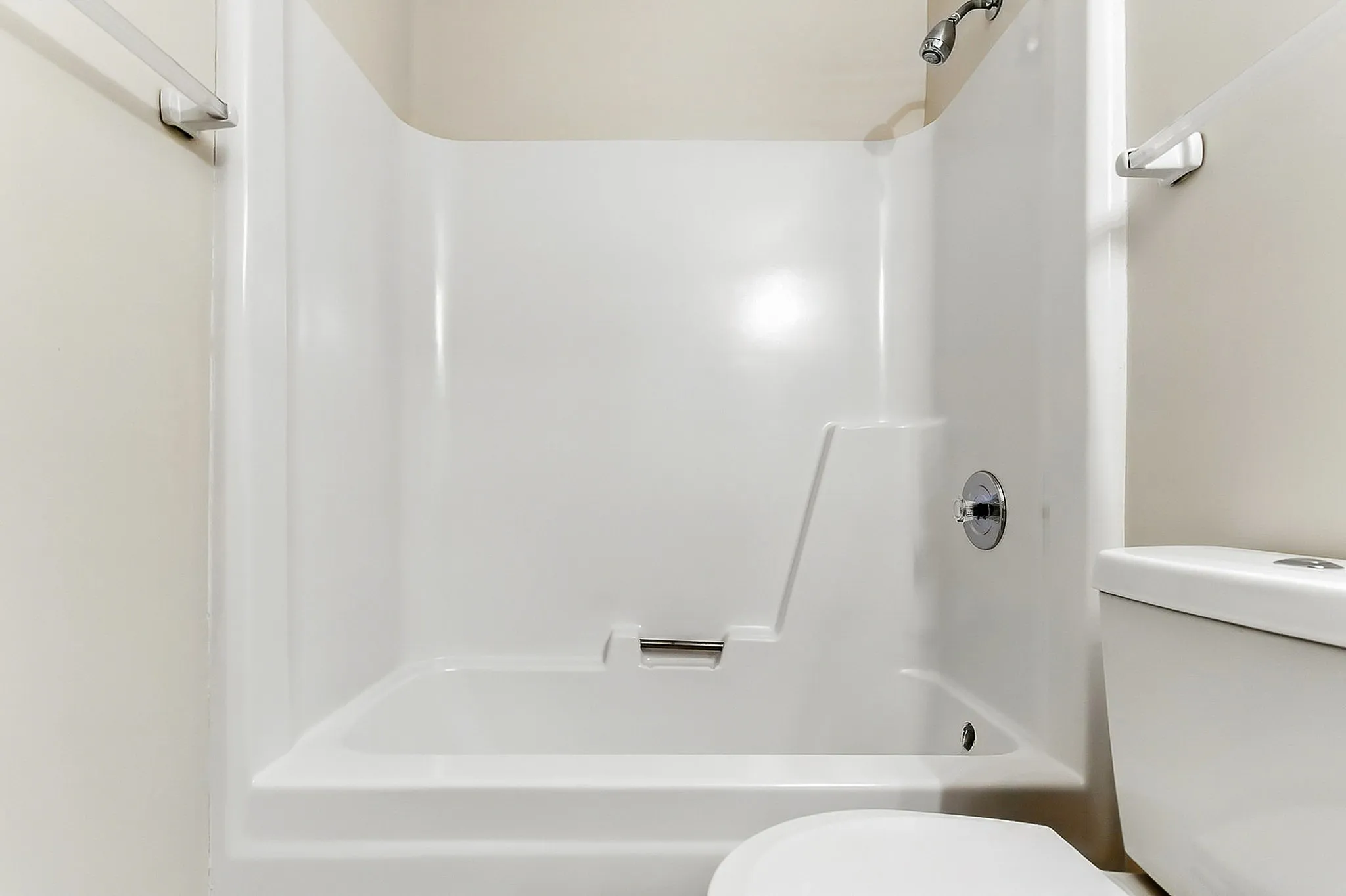 Spacious modern bathroom showcasing a sleek, white shower and tub combination with chic fixtures.