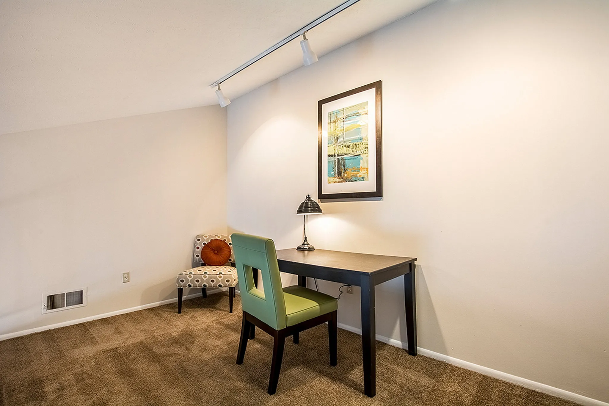 Cozy home office nook with a stylish desk, modern green chair, and decorative art piece enhancing the inviting ambiance.