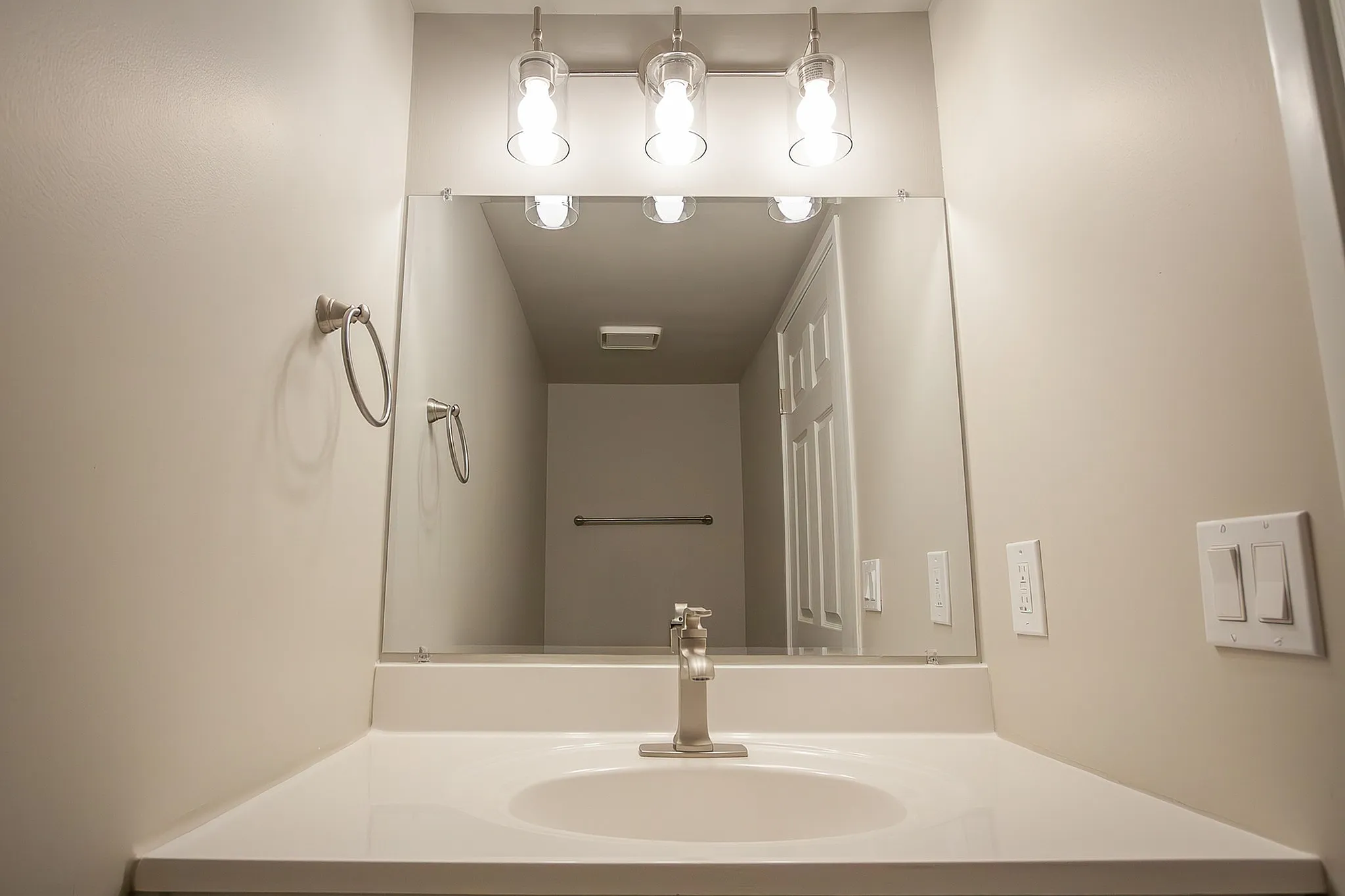 Bright and modern bathroom with sleek vanity, large mirror, and contemporary lighting.