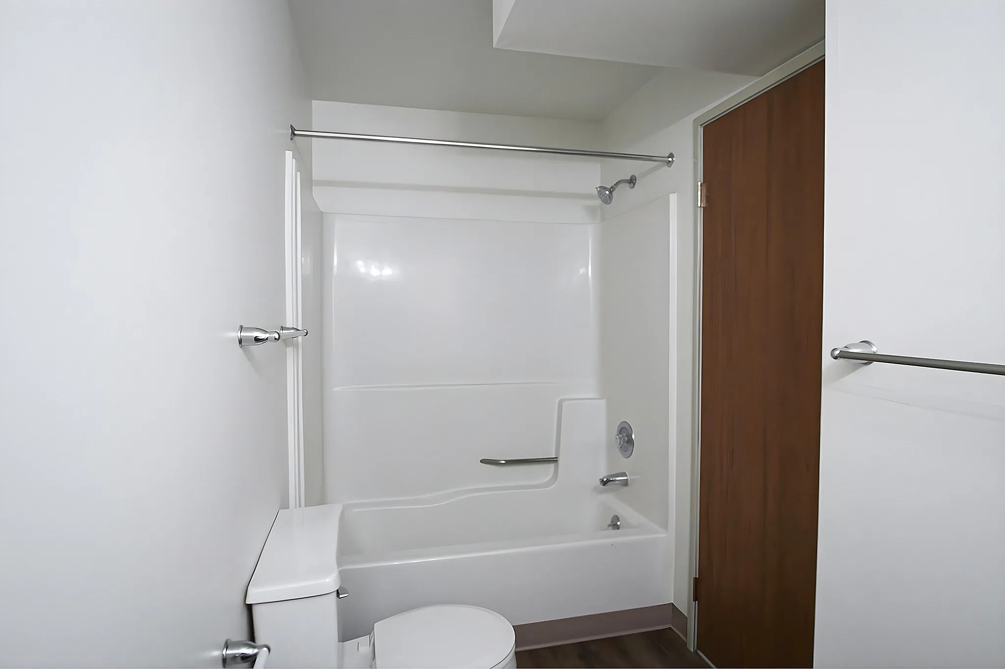 Sleek modern bathroom with elegant full-size bathtub, pristine white walls, and stylish wooden door.