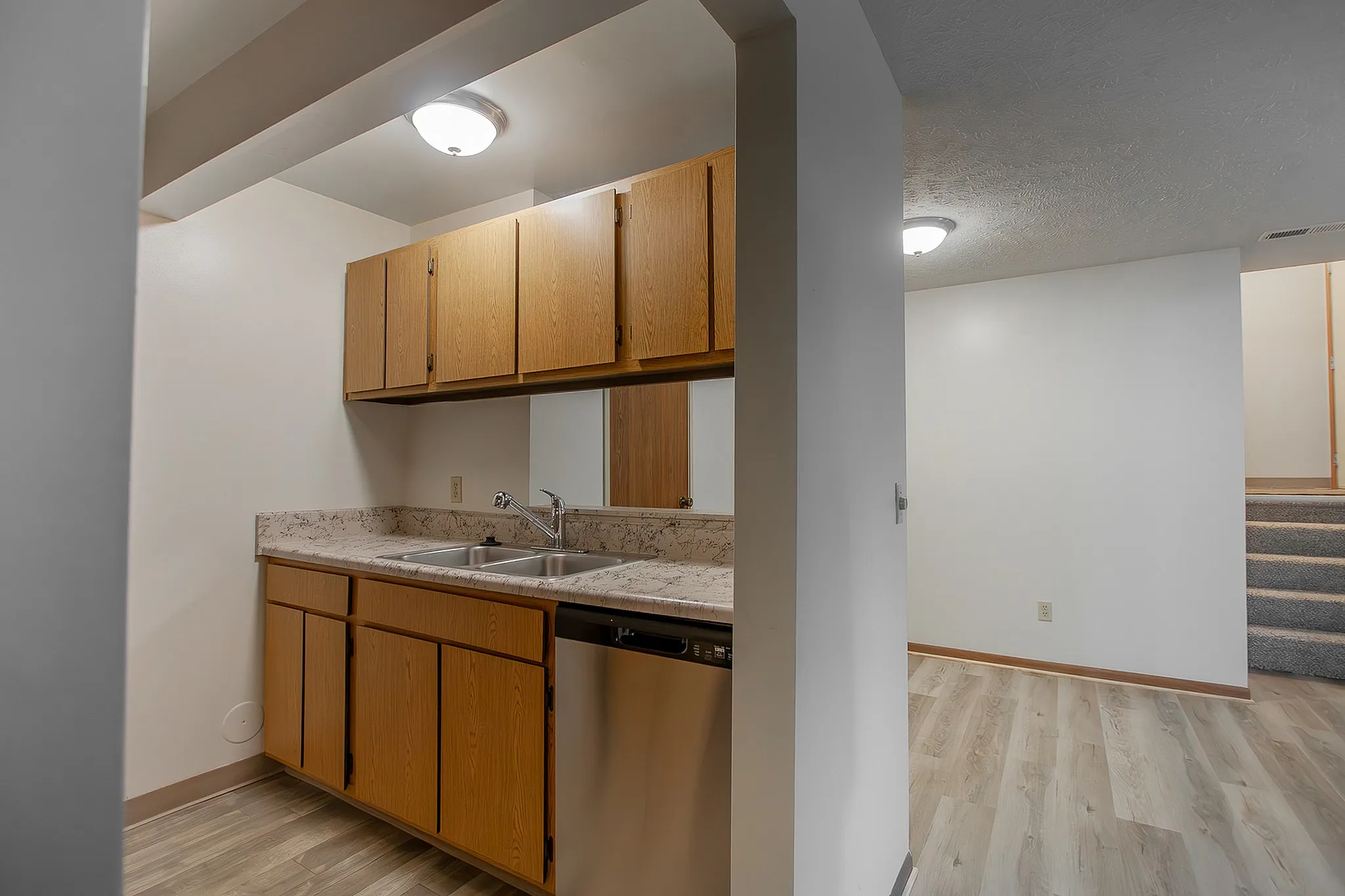 Charming kitchen space with sleek countertops, inviting wooden cabinets, and a modern stainless steel dishwasher, perfect for culinary adventures.