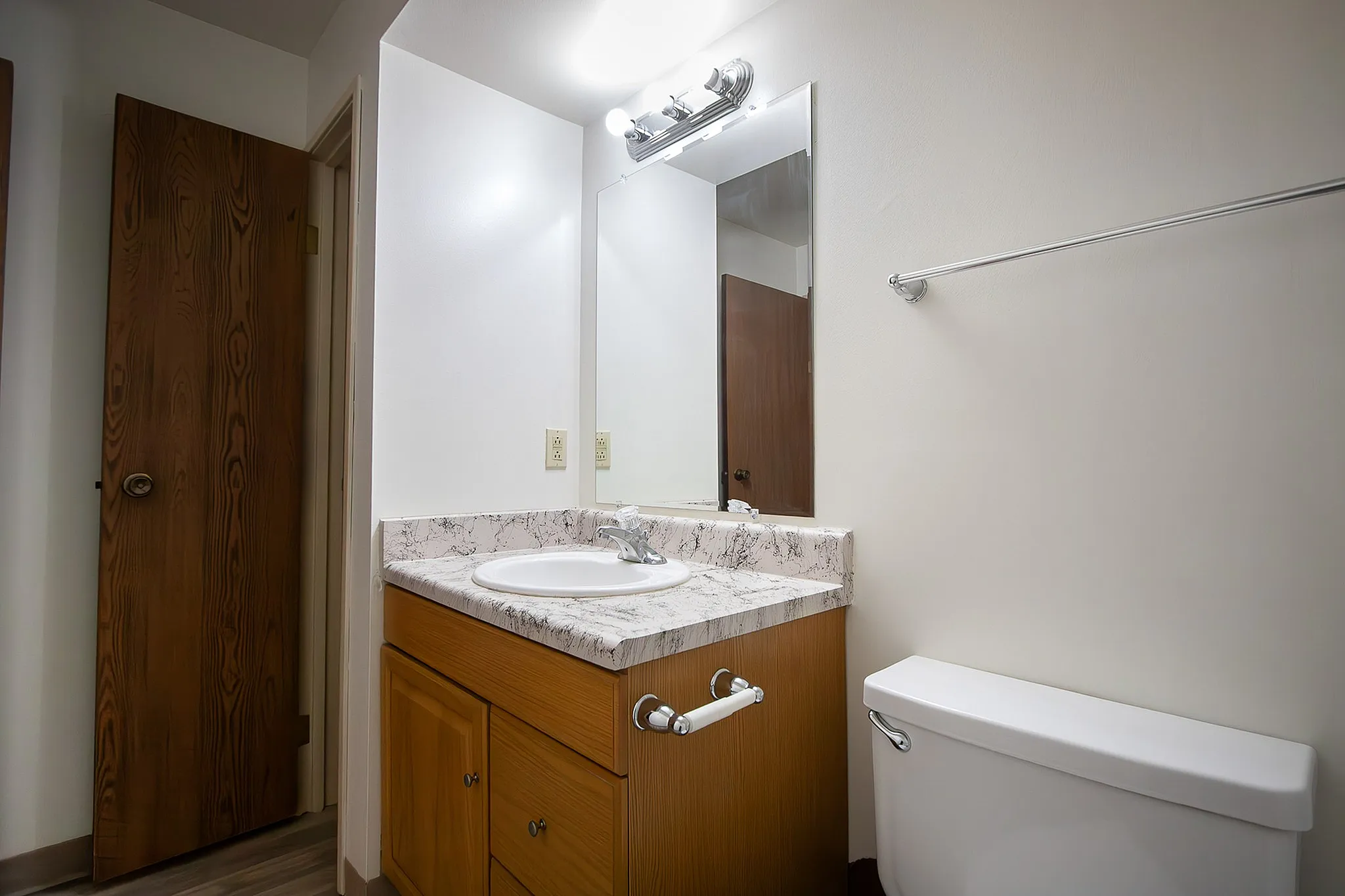 Bright and modern bathroom with sleek marble countertop, elegant wooden cabinetry, and a large mirror.