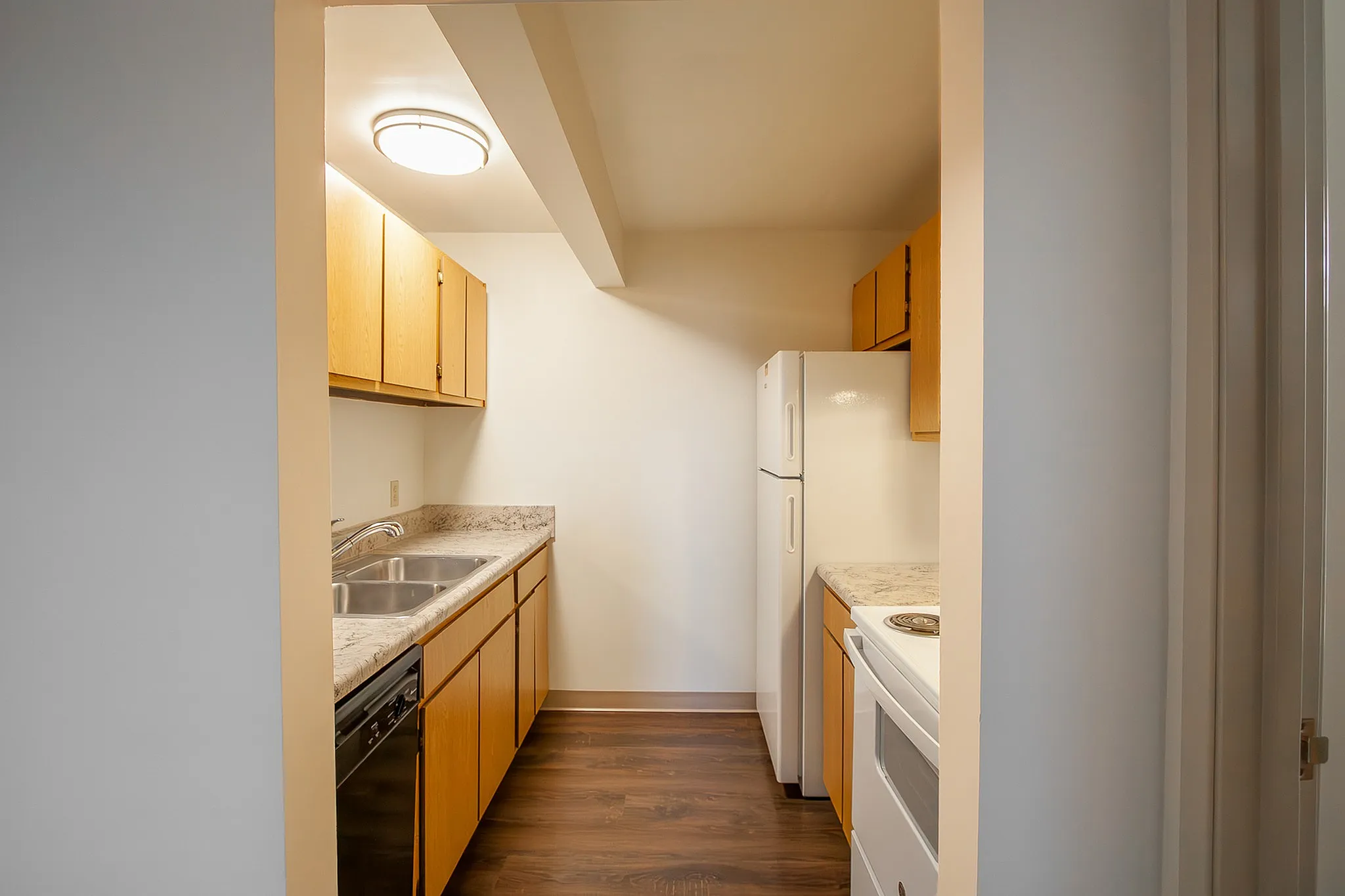 Charming and compact kitchen with modern appliances, warm wood cabinetry, and elegant marble countertops.