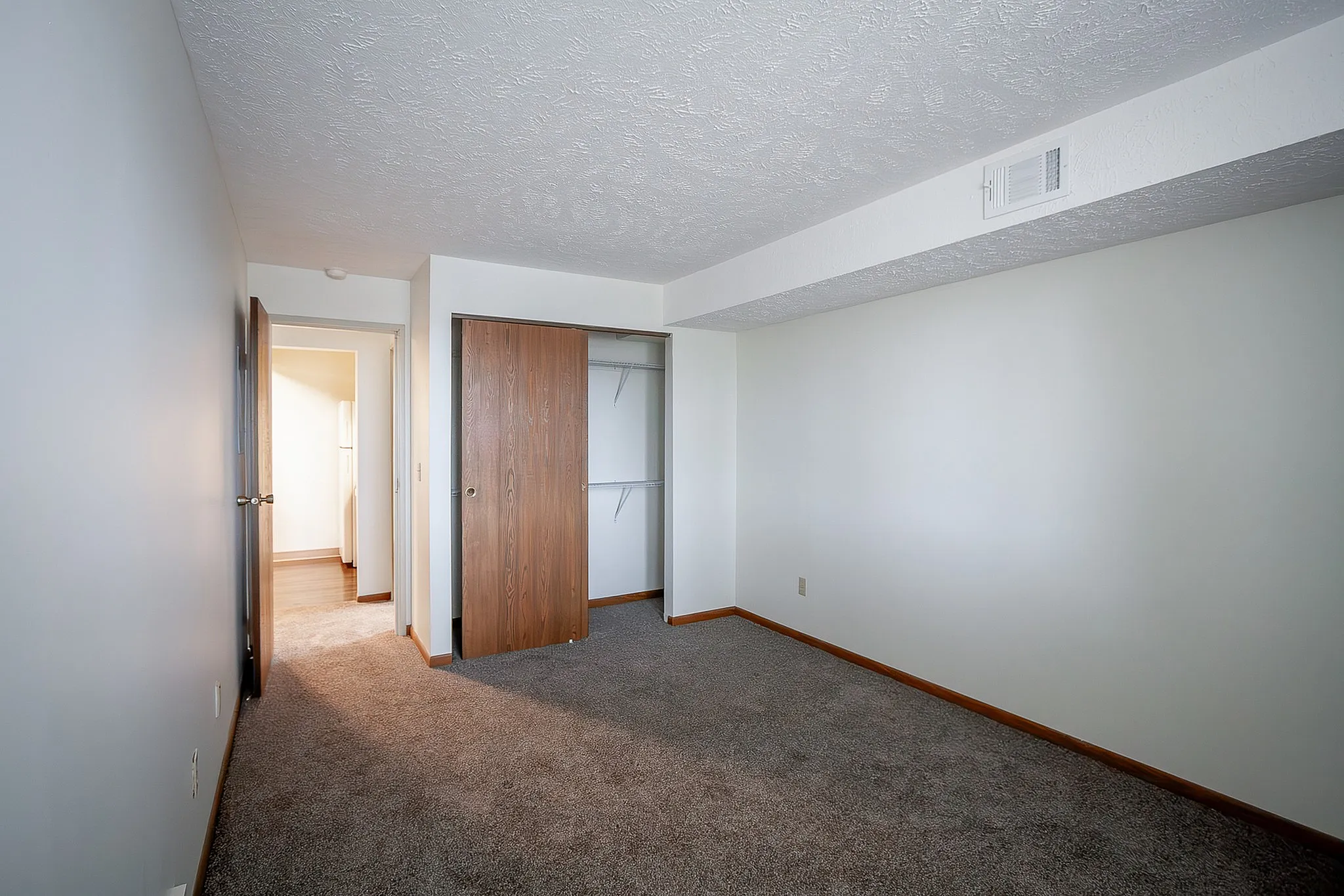 Cozy bedroom with plush carpeting, spacious closet, and natural lighting, perfect for relaxation.