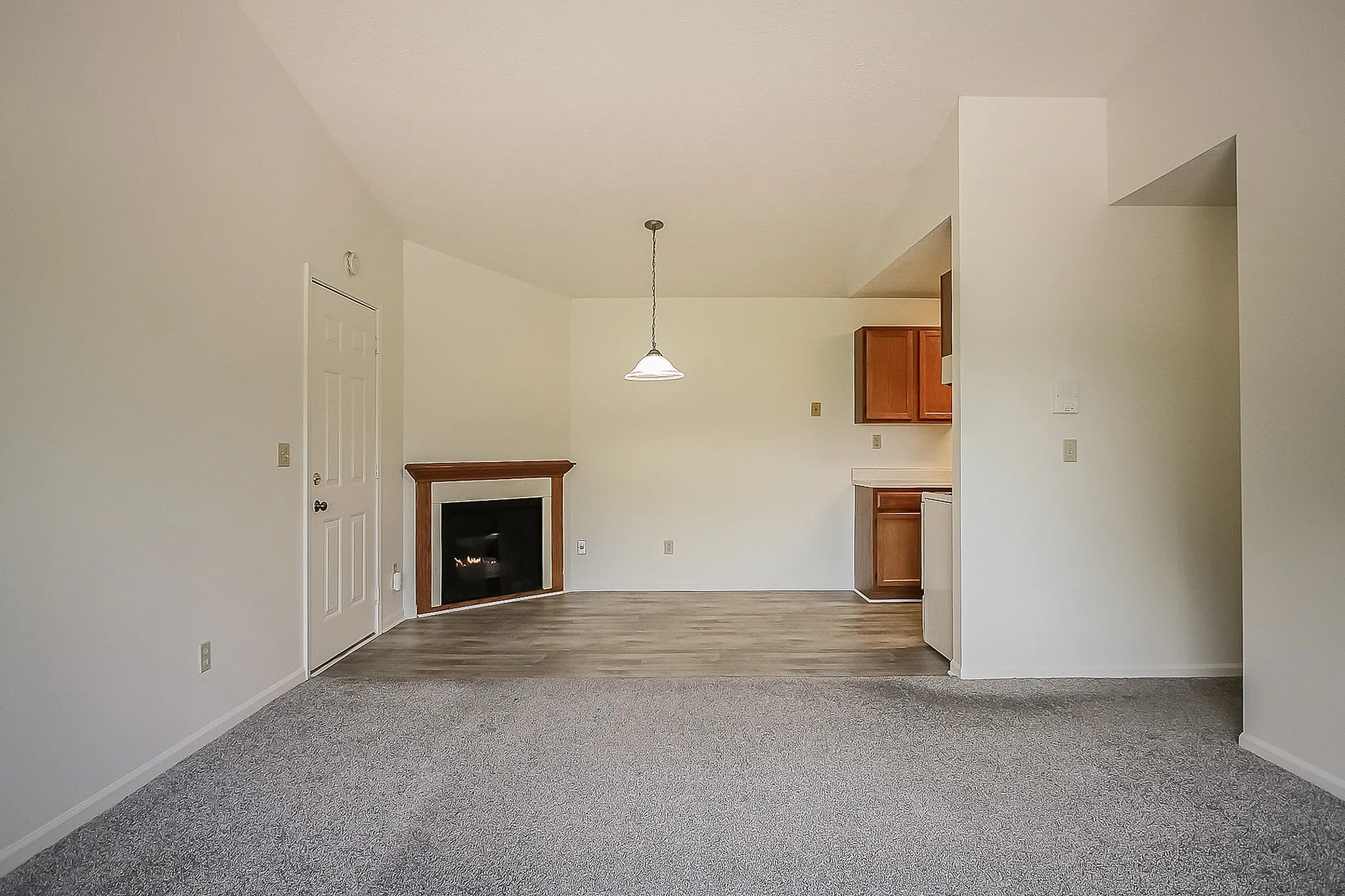 Bright and inviting living area with modern fireplace, elegant overhead lighting, and cozy kitchen nook in a contemporary apartment.