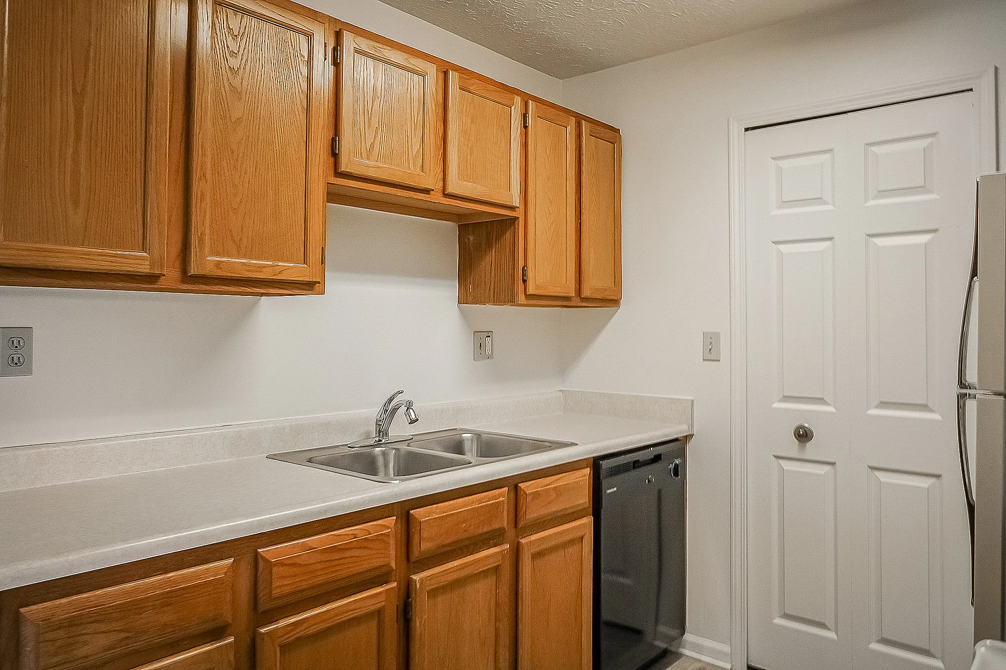 Modern kitchen featuring elegant wooden cabinets, dual sink, and sleek countertops for a stylish cooking space.