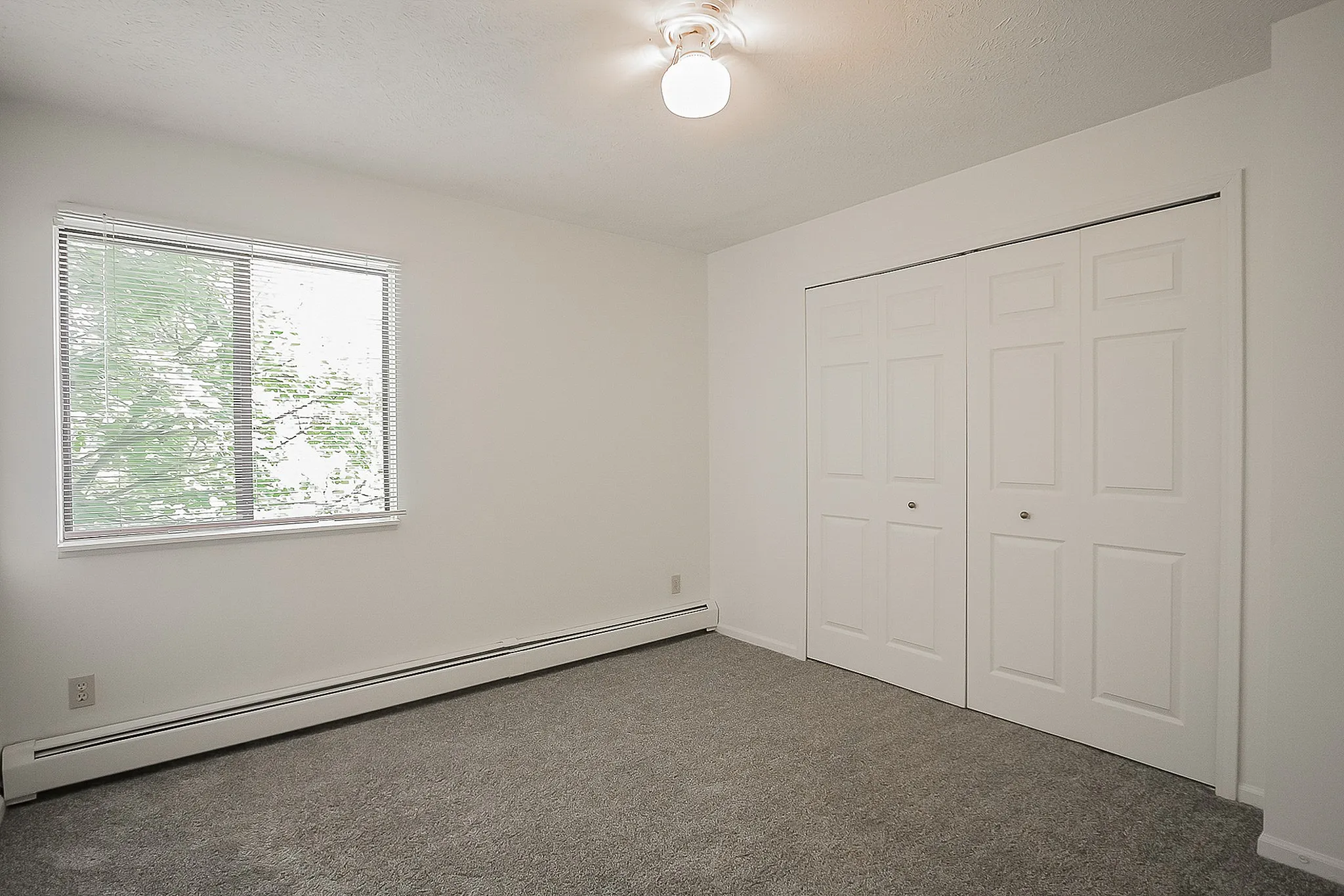 Bright and airy bedroom featuring new carpet, large closet, and window with scenic views.