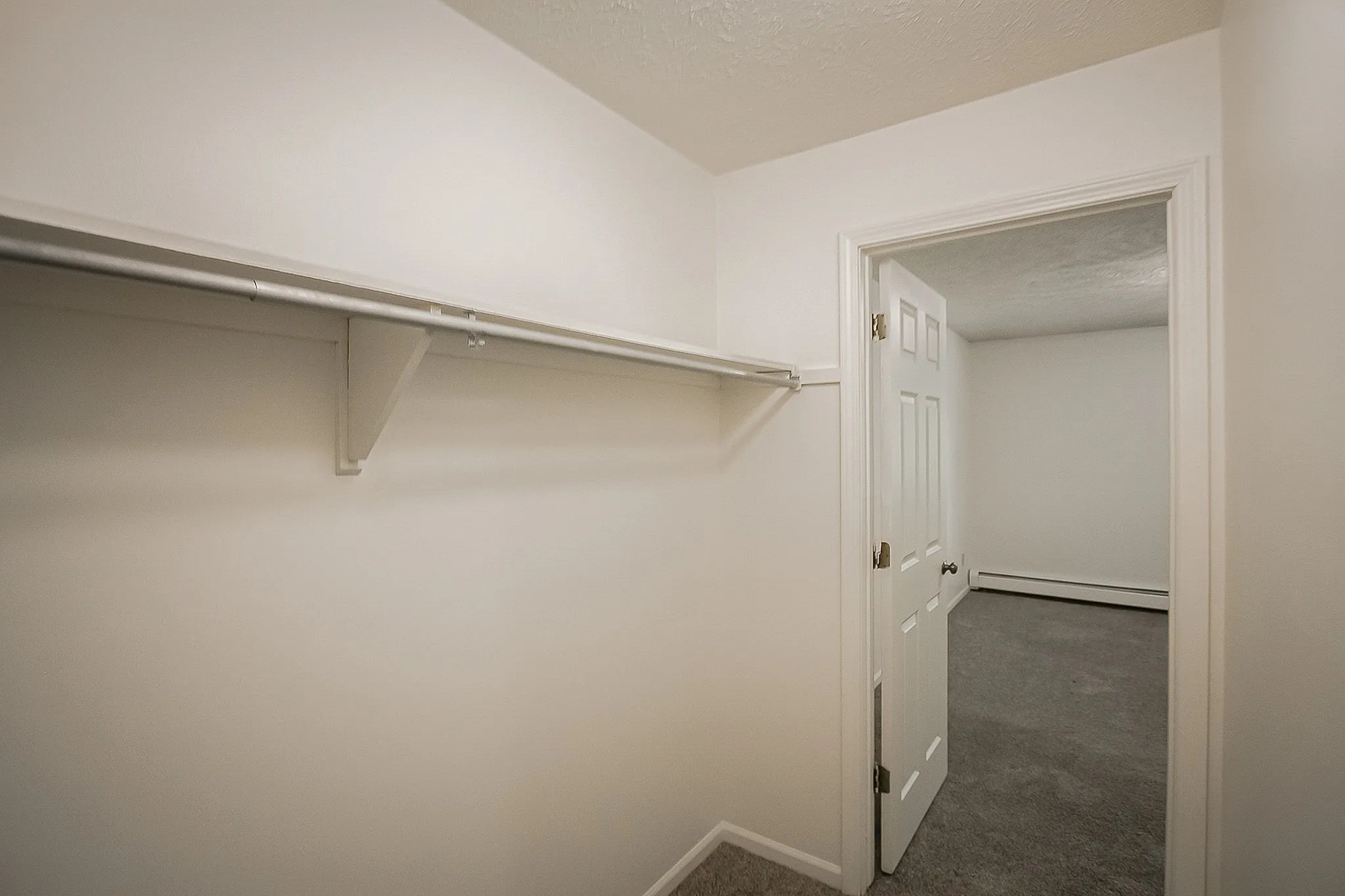Spacious walk-in closet with sleek shelving and neutral tones, offering ample storage space.