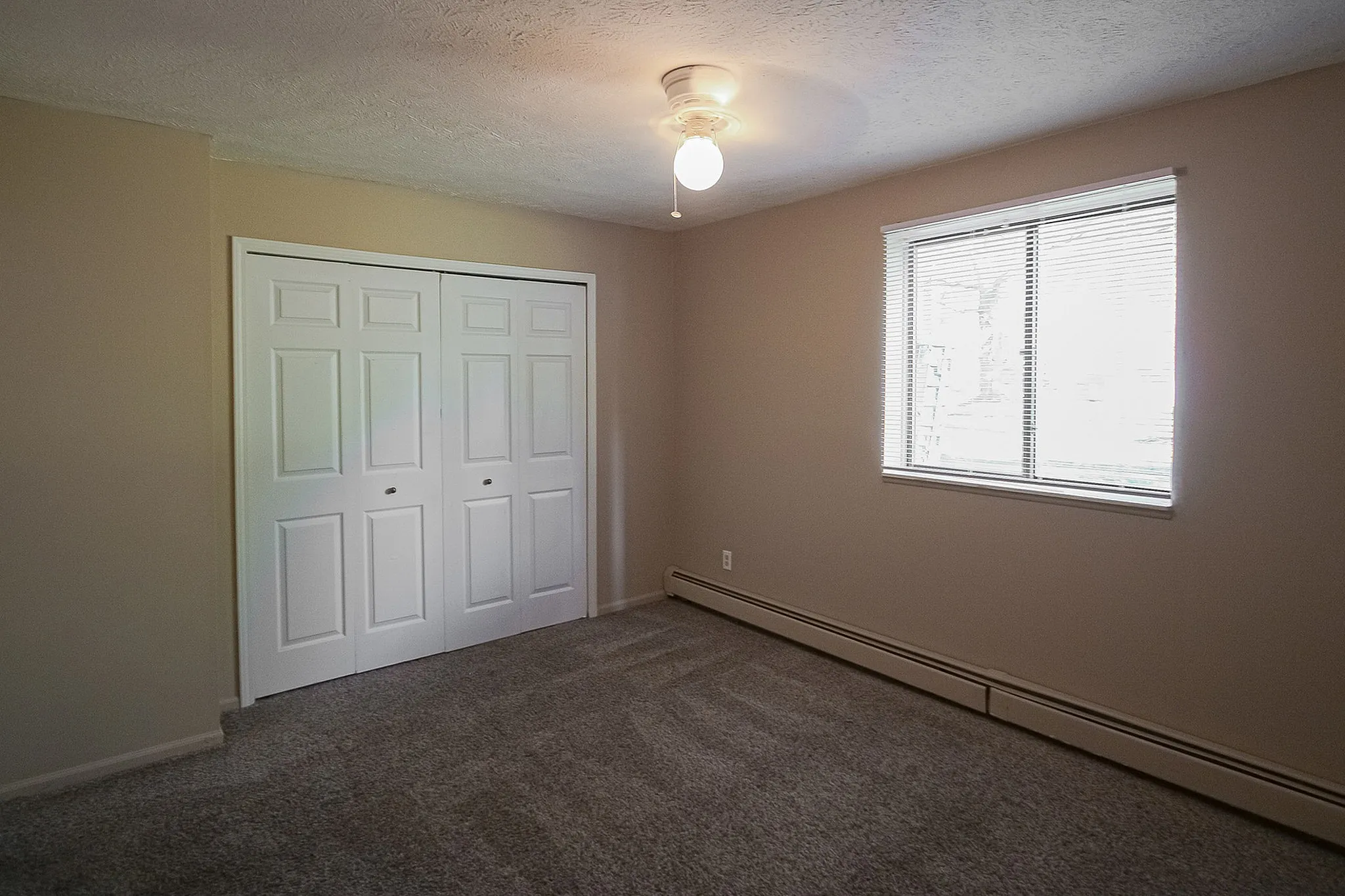 Bright and cozy bedroom with soft carpeting, a spacious closet with double doors, and a large window inviting natural light.
