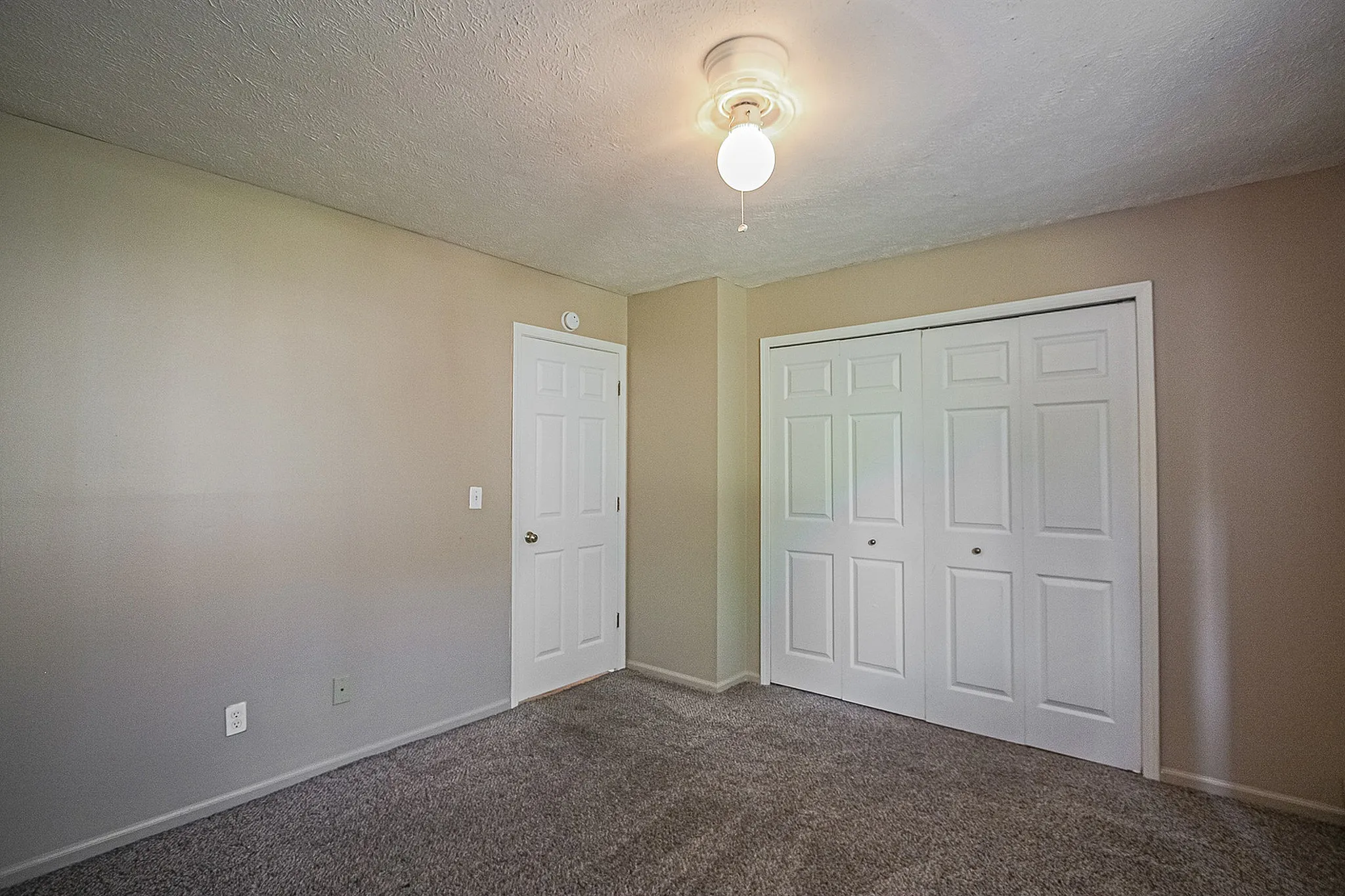 Inviting bedroom with plush carpet, ample closet space, and warm neutral tones promising a cozy retreat.