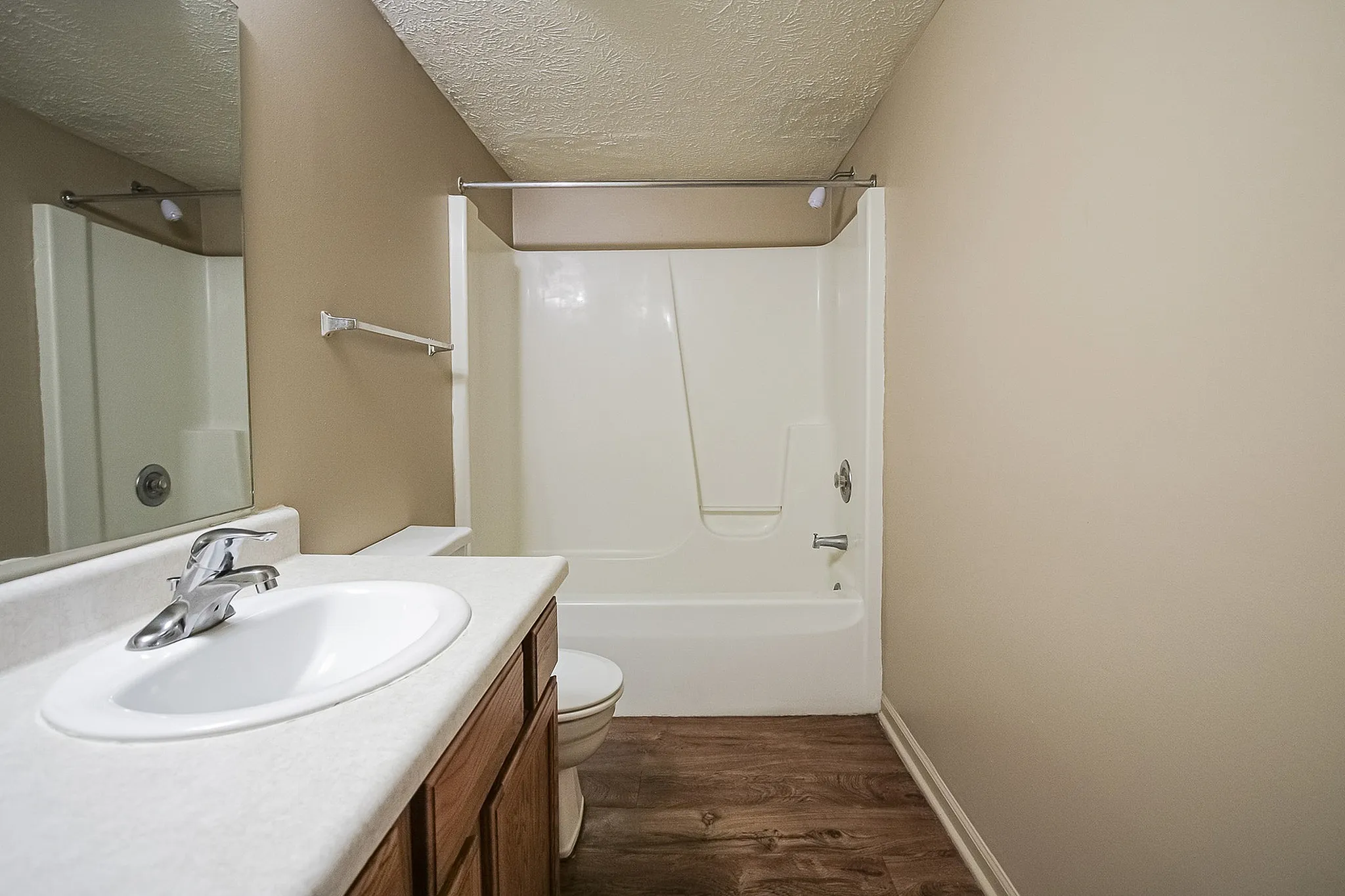 Bright and modern bathroom featuring a sleek white bathtub, polished sink, and elegant wood flooring.