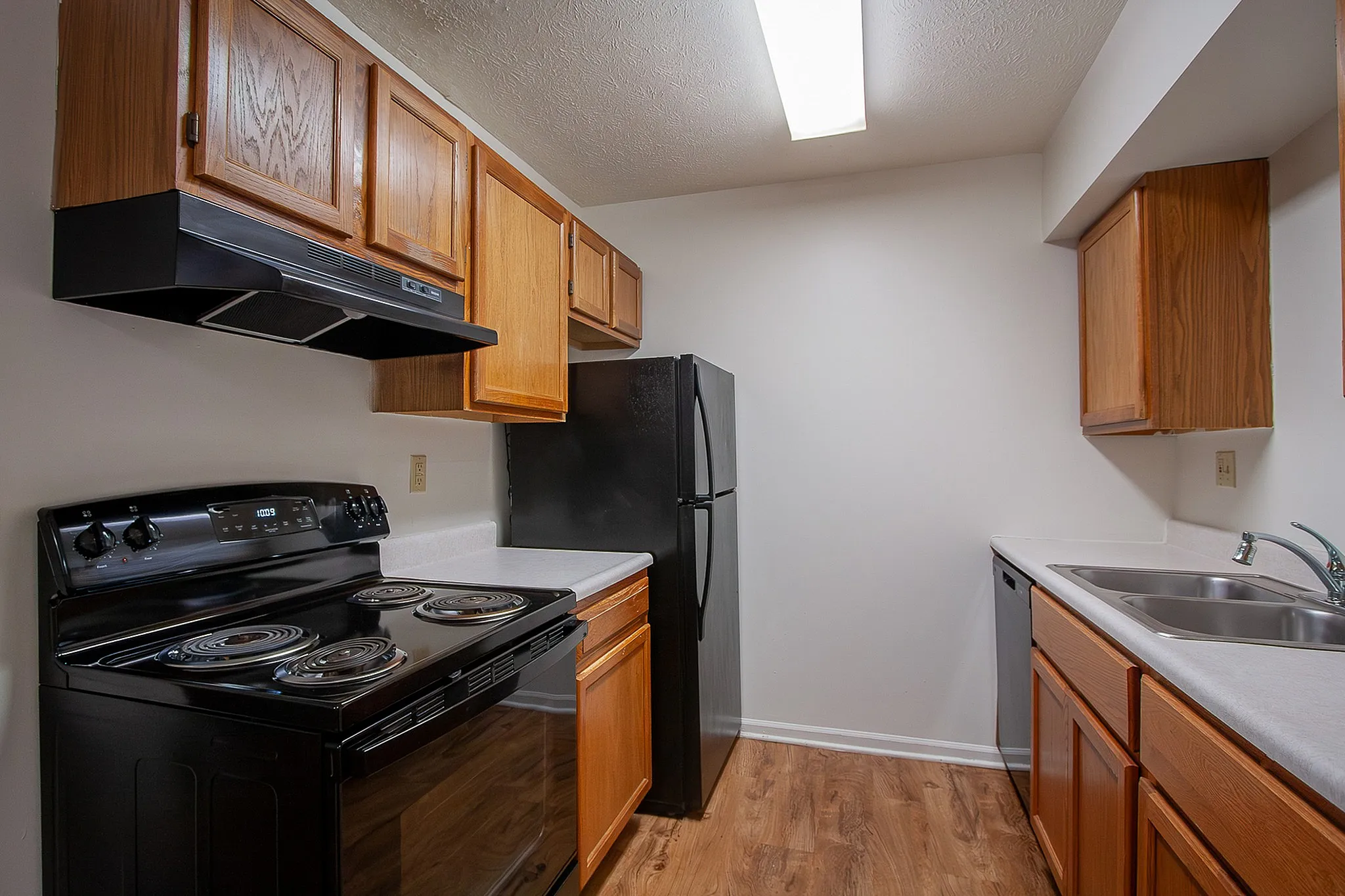Contemporary kitchen with sleek black appliances, warm wooden cabinetry, and spacious countertops, perfect for culinary creations.