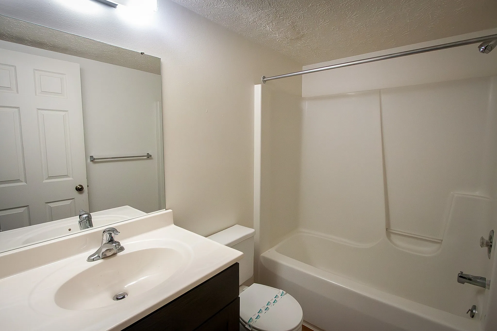 Modern bathroom with elegant fixtures, a sleek white vanity, and a refreshing shower-tub combo, offering a clean and inviting ambiance.