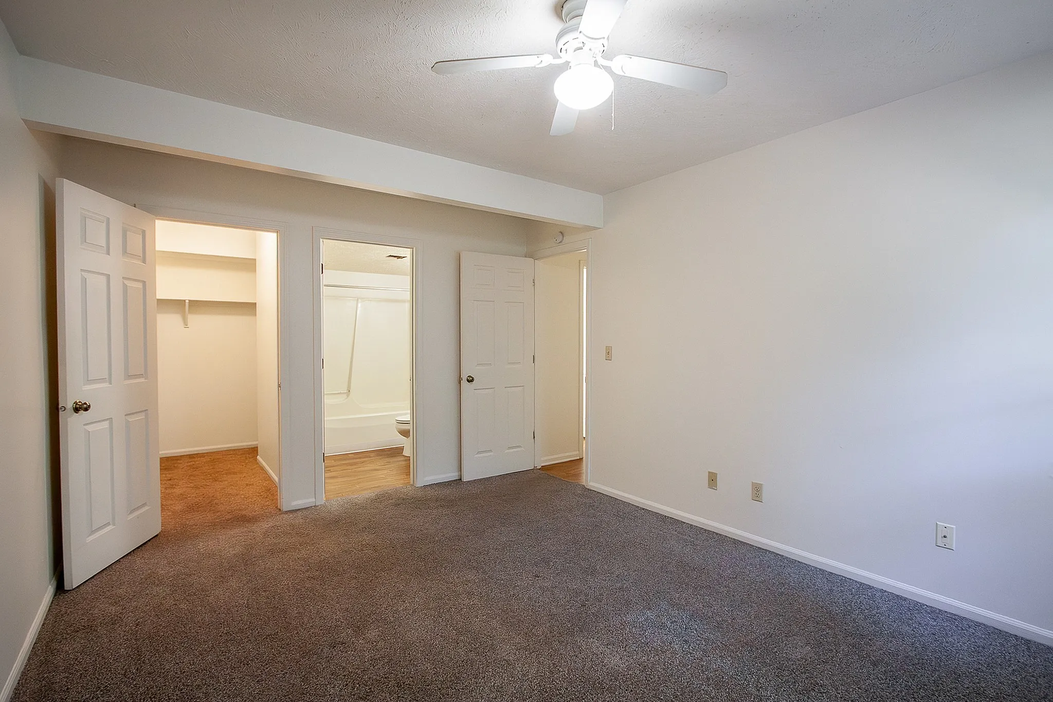 Inviting bedroom with plush carpet, ample natural light, and convenient access to a spacious closet and modern bathroom.