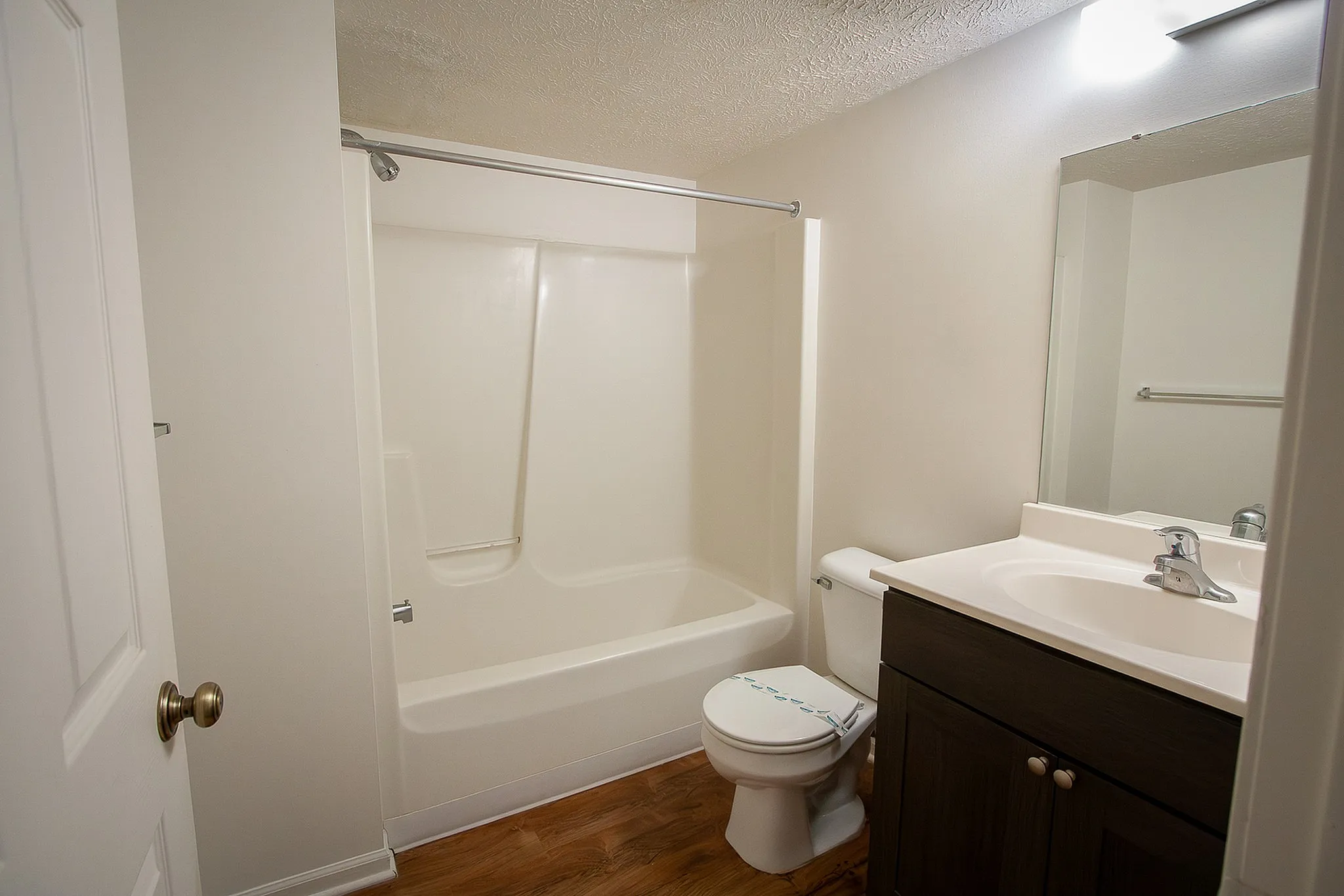 Bright and modern bathroom featuring a sleek bathtub, elegant sink with vanity, and rich wood flooring.