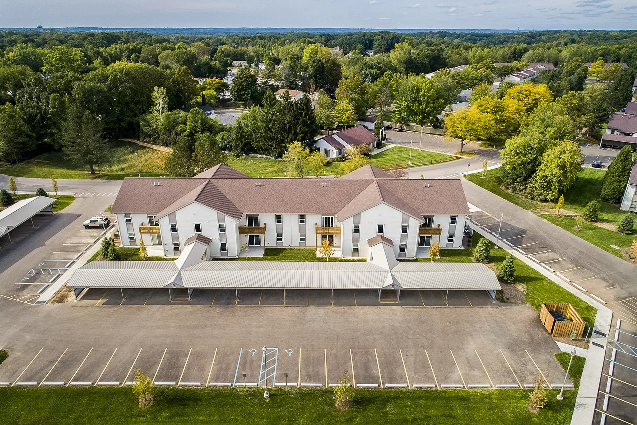Charming apartment complex surrounded by lush greenery, featuring ample parking and inviting residential appeal.