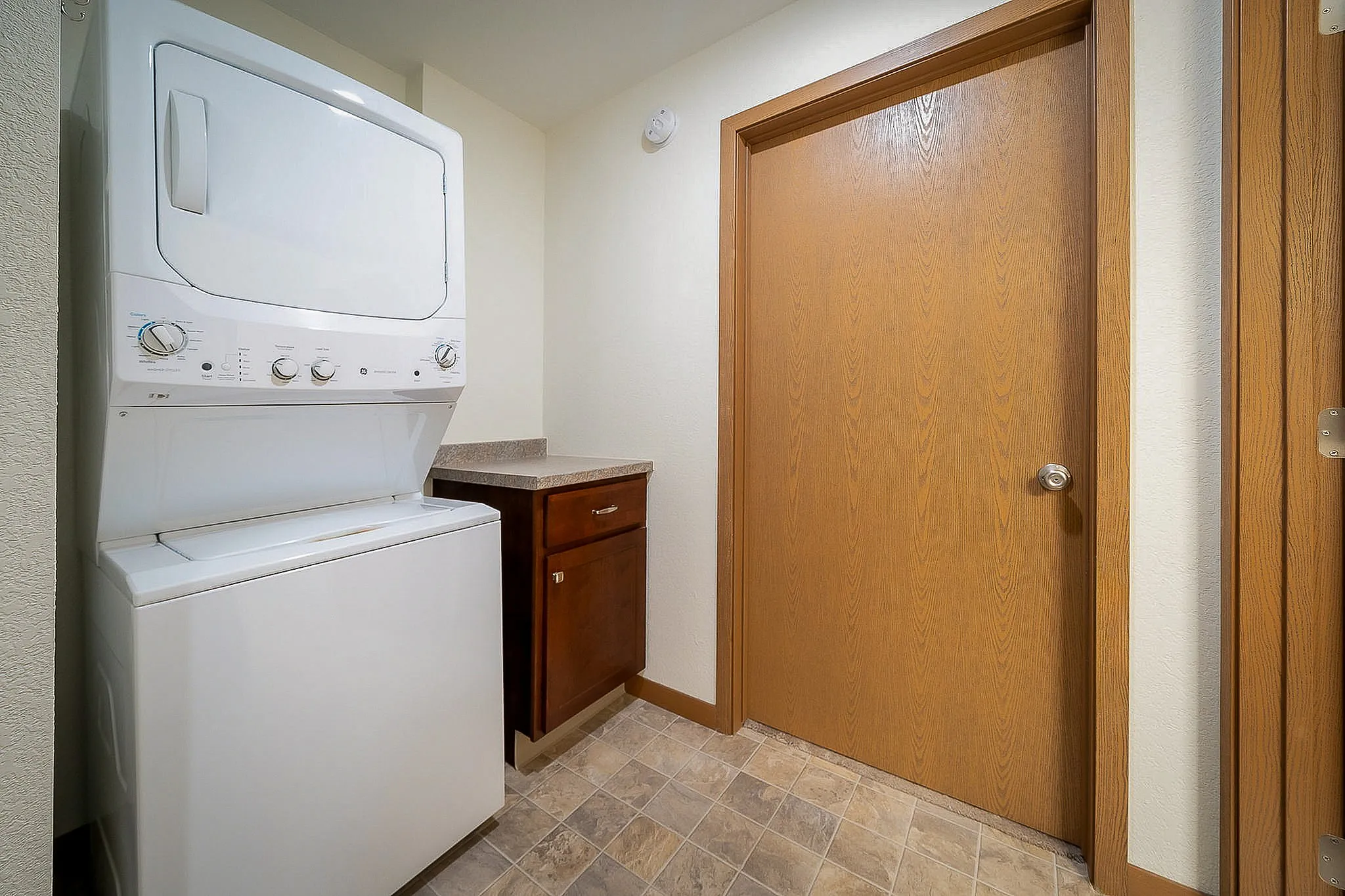 Convenient laundry room featuring a modern stacked washer and dryer with sleek cabinetry for storage, ideal for efficient living.