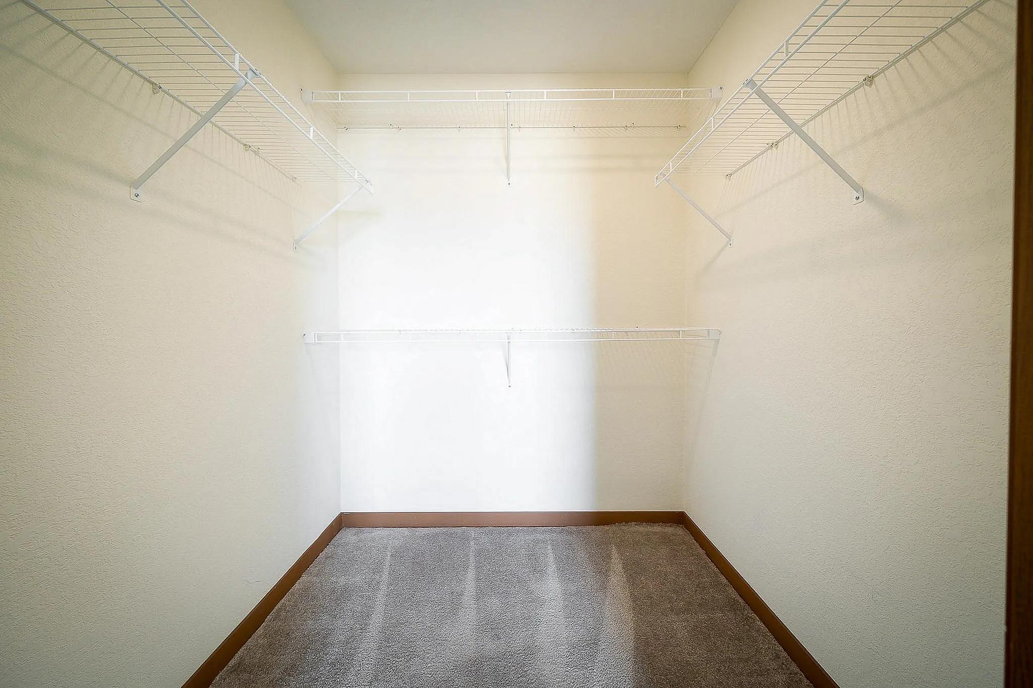 Spacious walk-in closet with ample shelving and neutral colors, perfect for organizing.