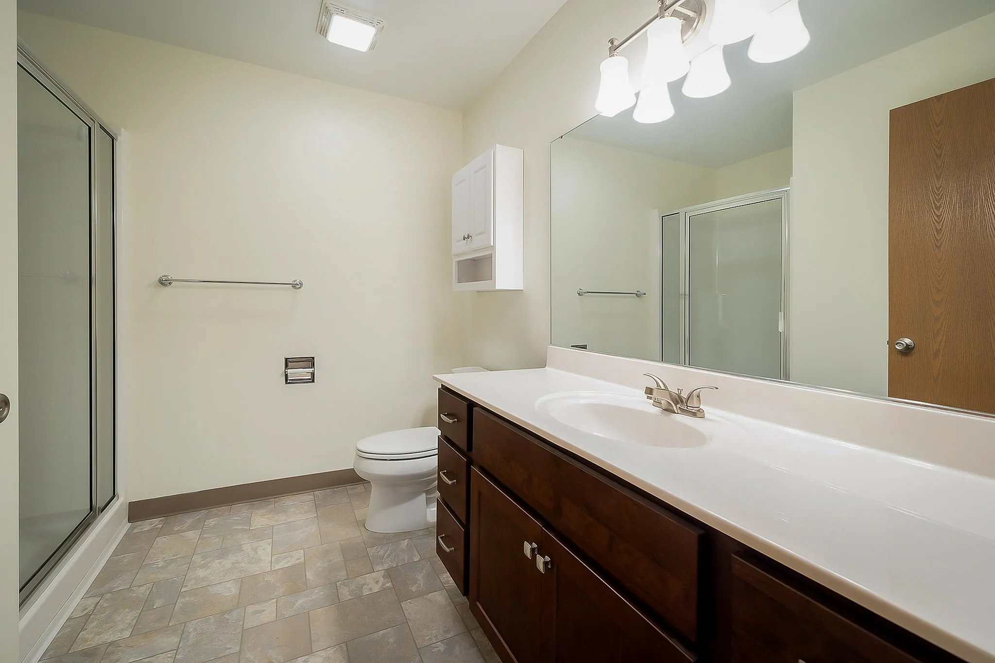 Modern bathroom with elegant lighting, spacious vanity, and sleek shower enclosure.