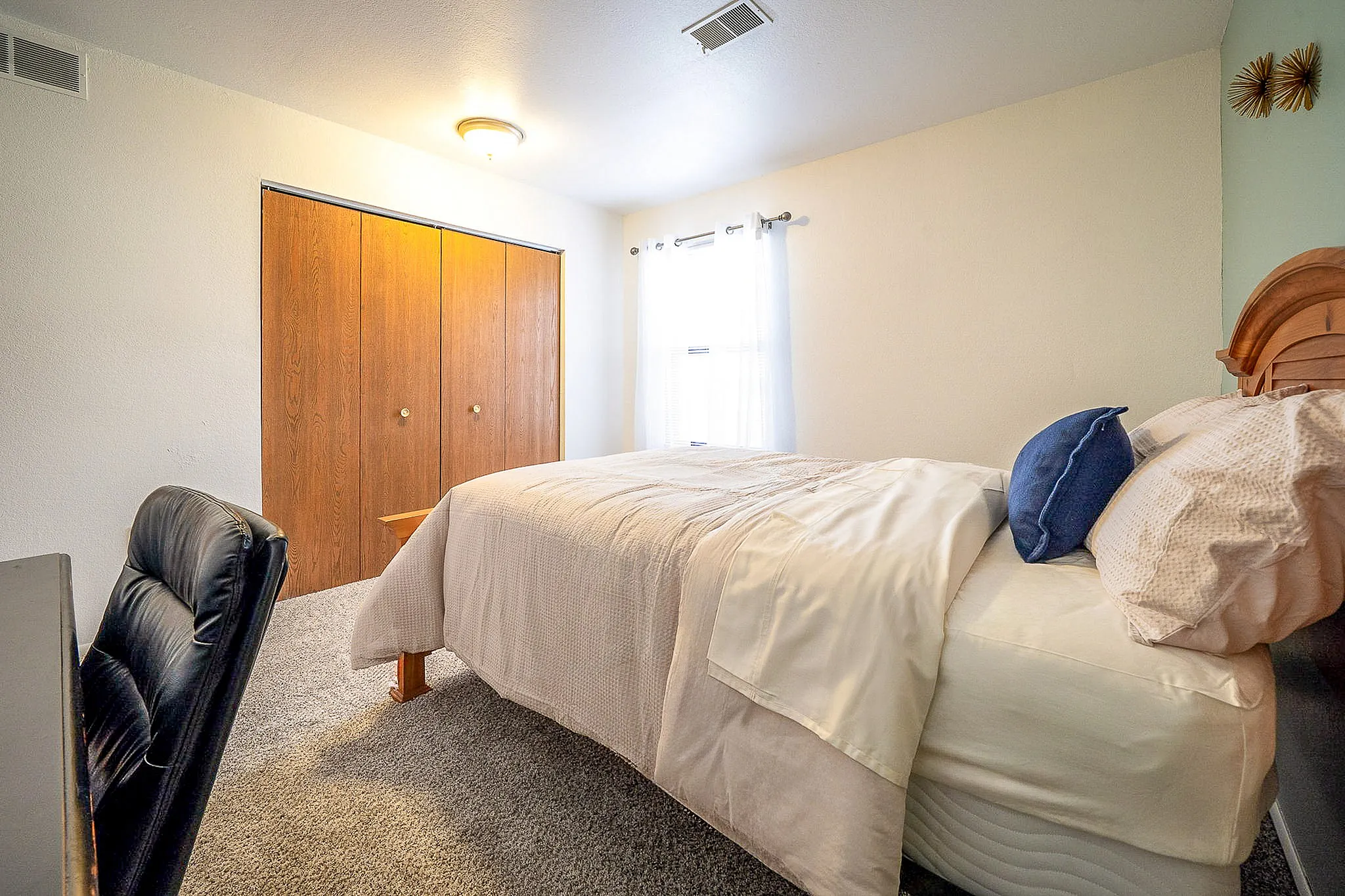 Bright and cozy bedroom featuring a comfortable bed with plush pillows, soft carpeting, and ample closet space for storage.
