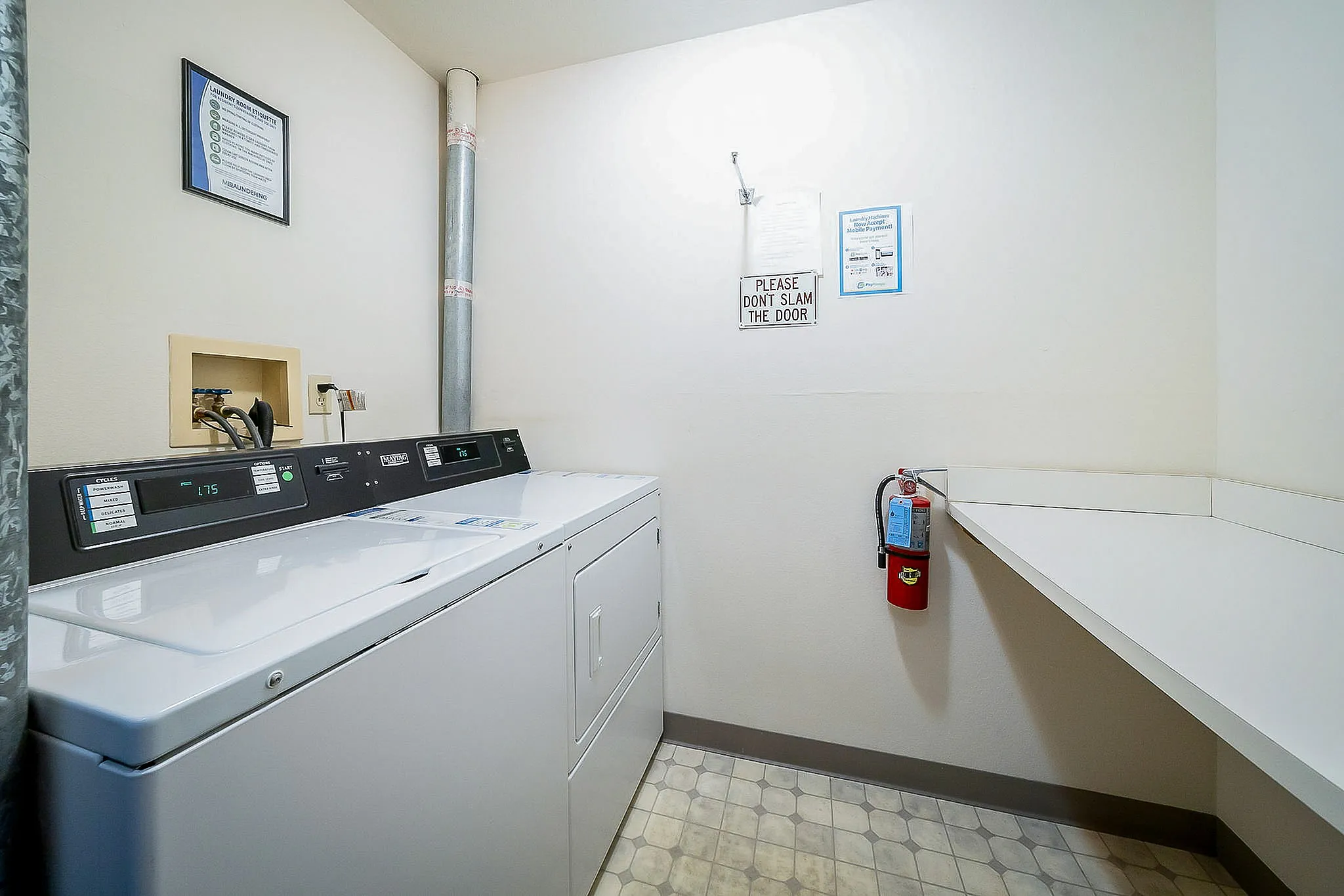 Modern laundry room featuring a sleek washer and dryer, ample folding space, and practical wall storage.